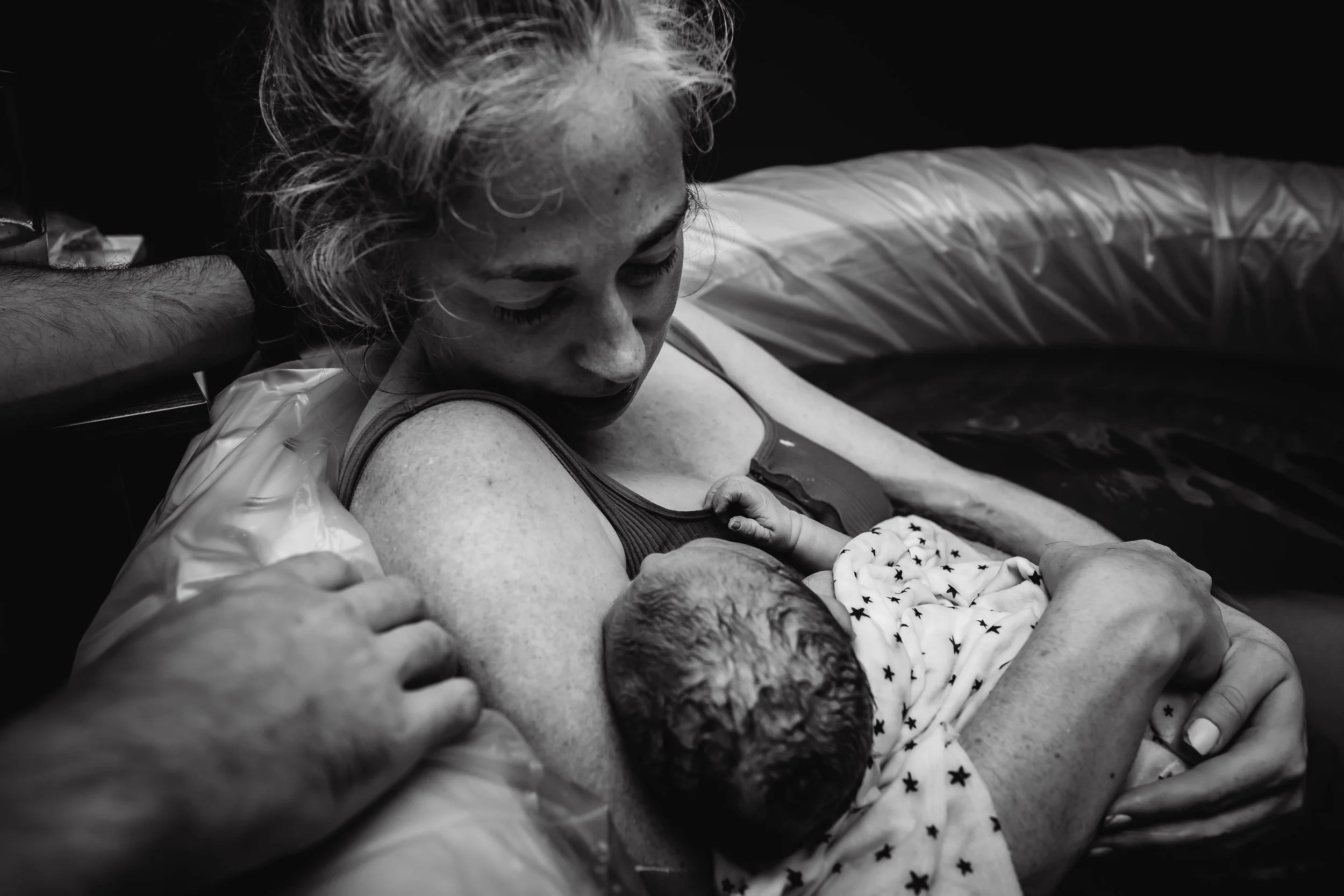 A woman is holding a newborn baby after an at home childbirth.