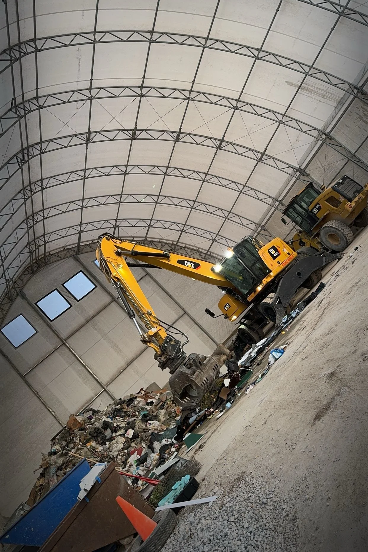 This image displays the material handler posed in action. There is waste behind the material handler arm and bucket - waiting to be properly sorted.