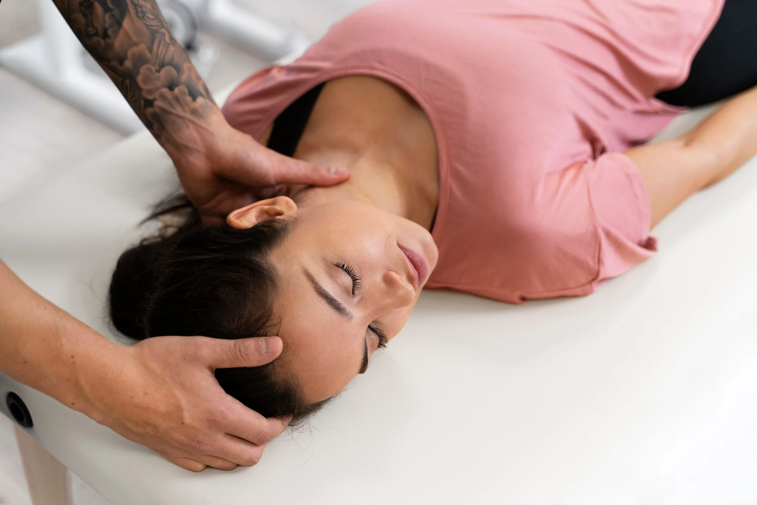 Eine Frau liegt auf einer Liege und erhält eine Hals- und Nackenmassage von einem Masseur