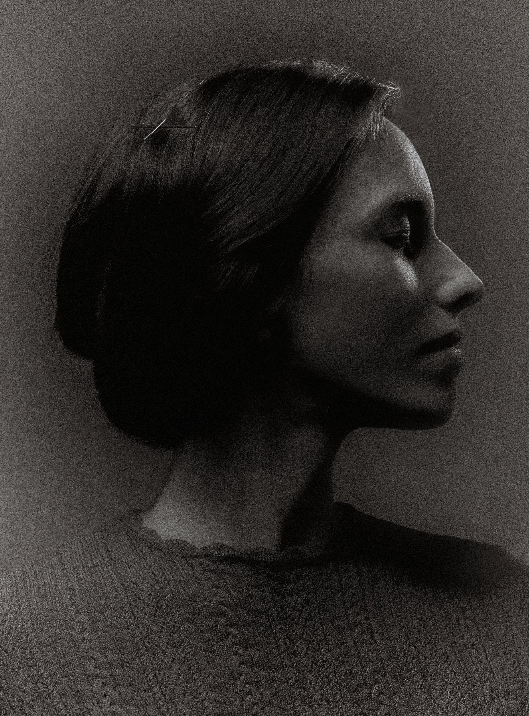 Profil de femme en noir et blanc, cheveux coiffés en chignon, regardant vers la droite.