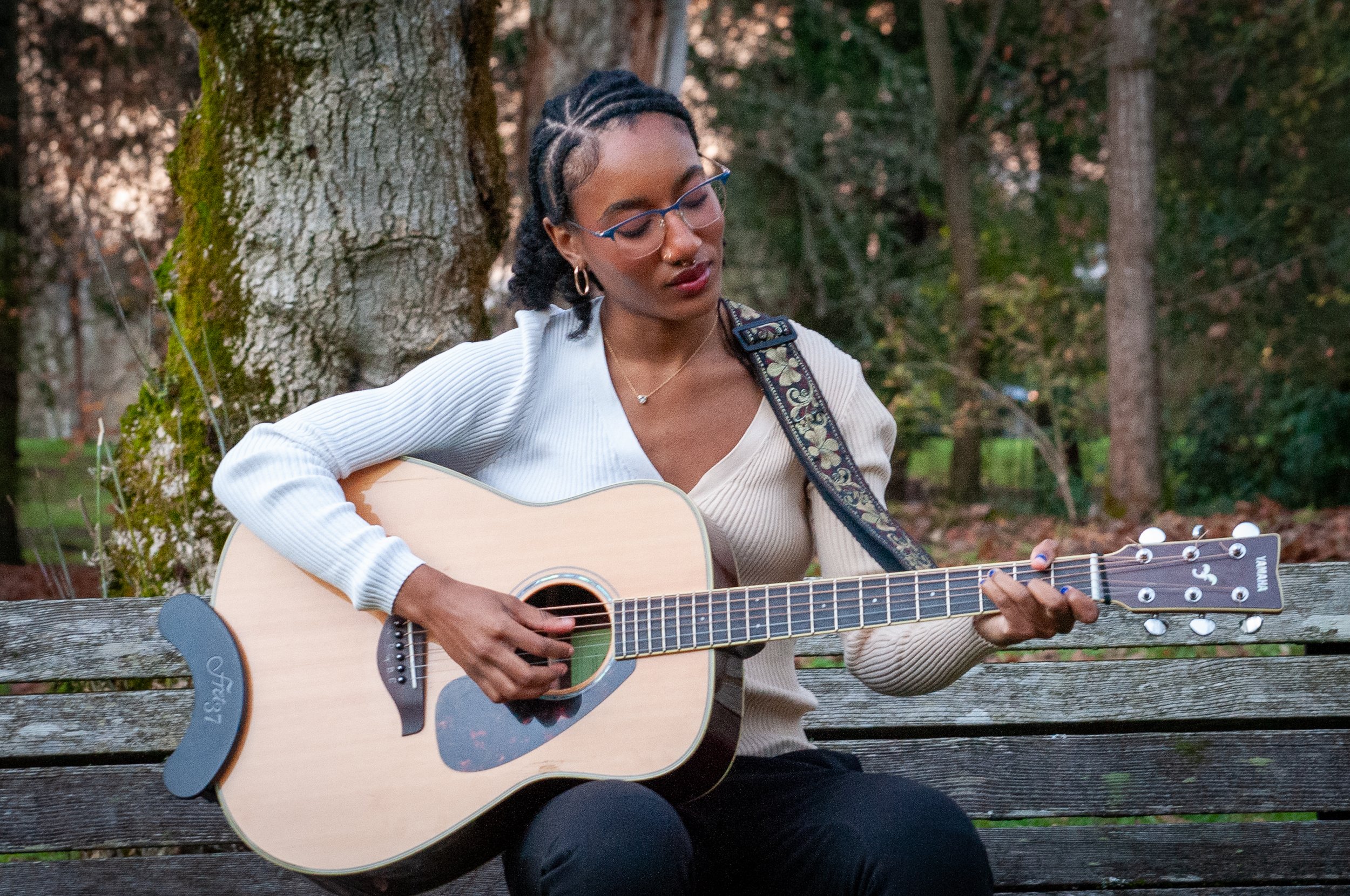 black woman looking at guitar and playing