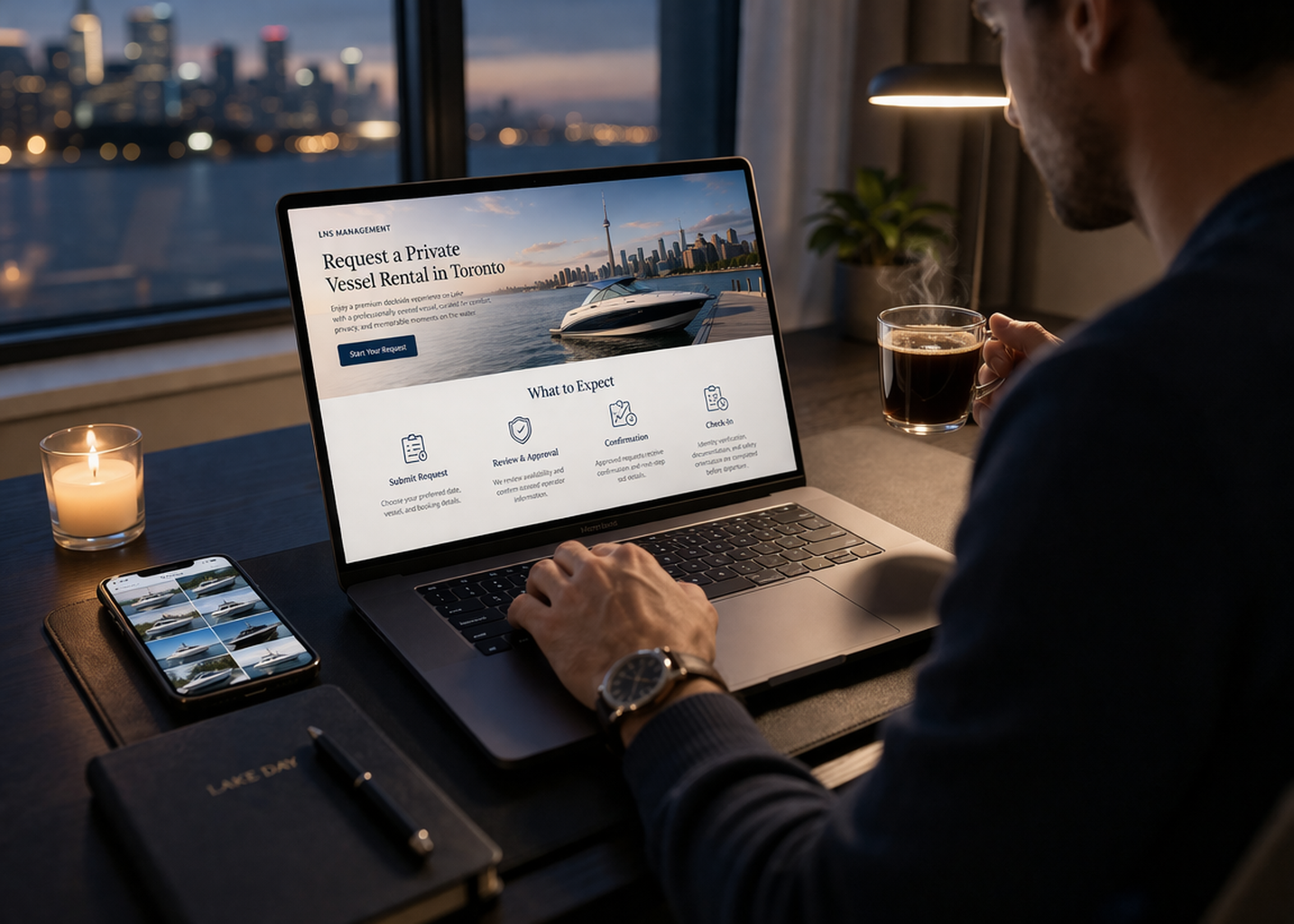 A man sitting at a desk with a laptop, looking at a website for private vessel rental in Toronto, with a city skyline and boat dock visible through the window. He is drinking coffee and has a smartphone, a candle, a notebook, and a pen on the desk.