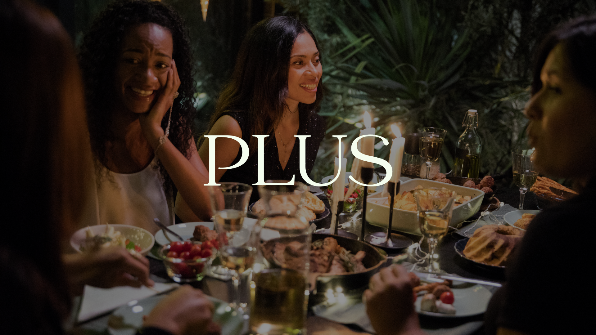 Group of women enjoying a dinner party outdoors at night with candles and a variety of dishes on the table.