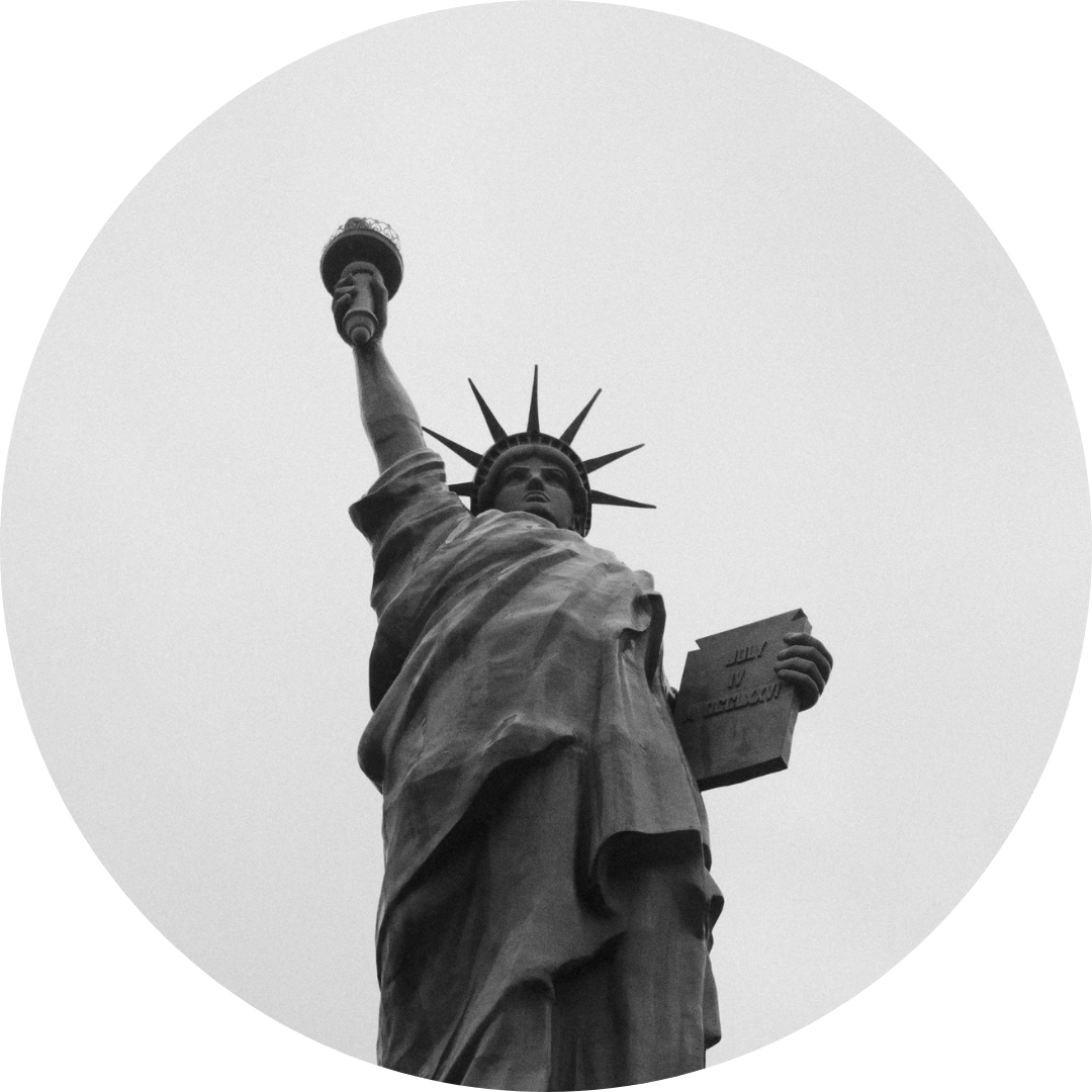 Black and white photo of the Statue of Liberty holding a torch up high and a tablet in her other hand, with a spiked crown on her head