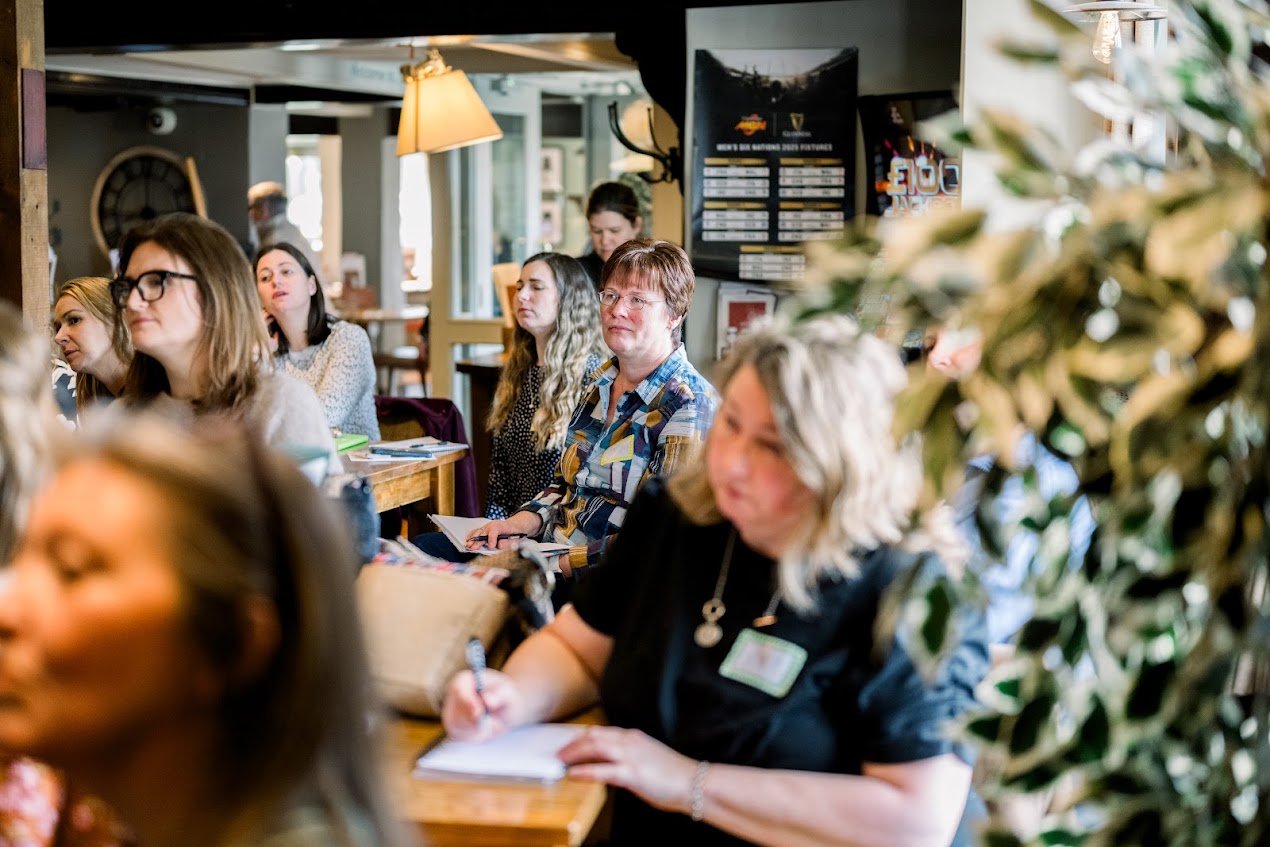 an image of Jane sitting in the middle of a crowd intently listening to the guest speaker at one of our events at bury st edmunds