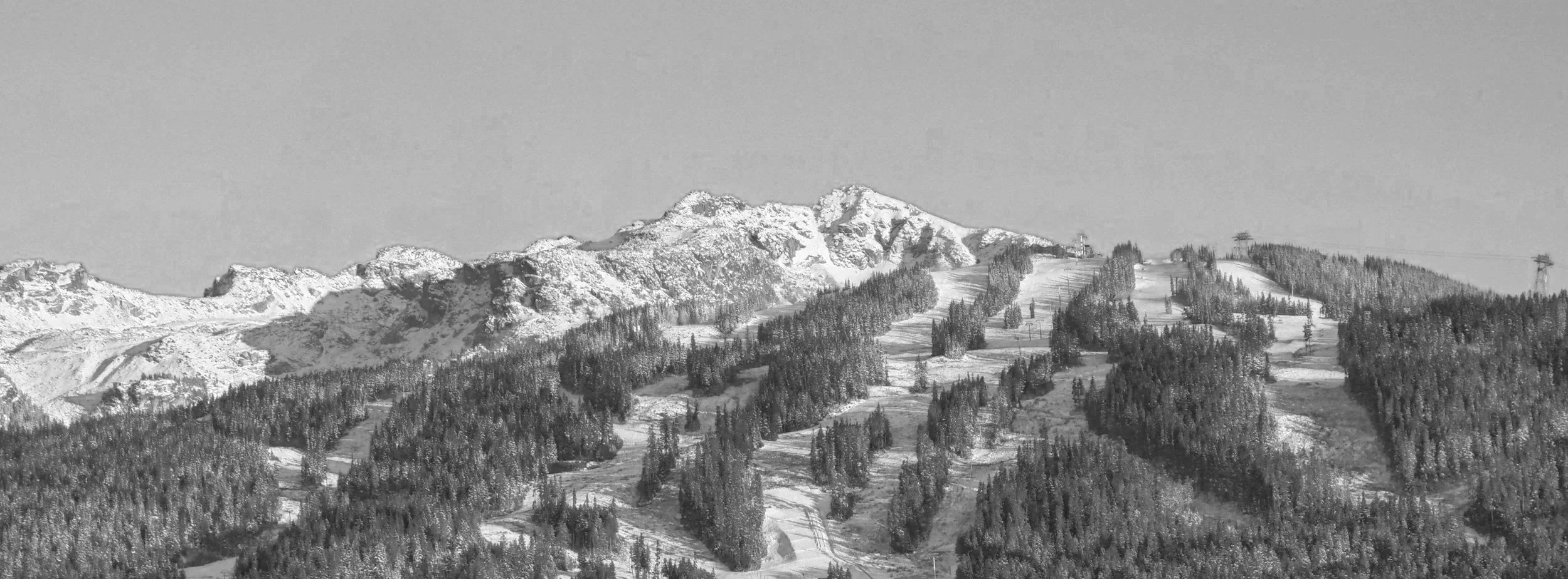 Snow-covered mountain range with ski slopes and ski lifts in a winter landscape.