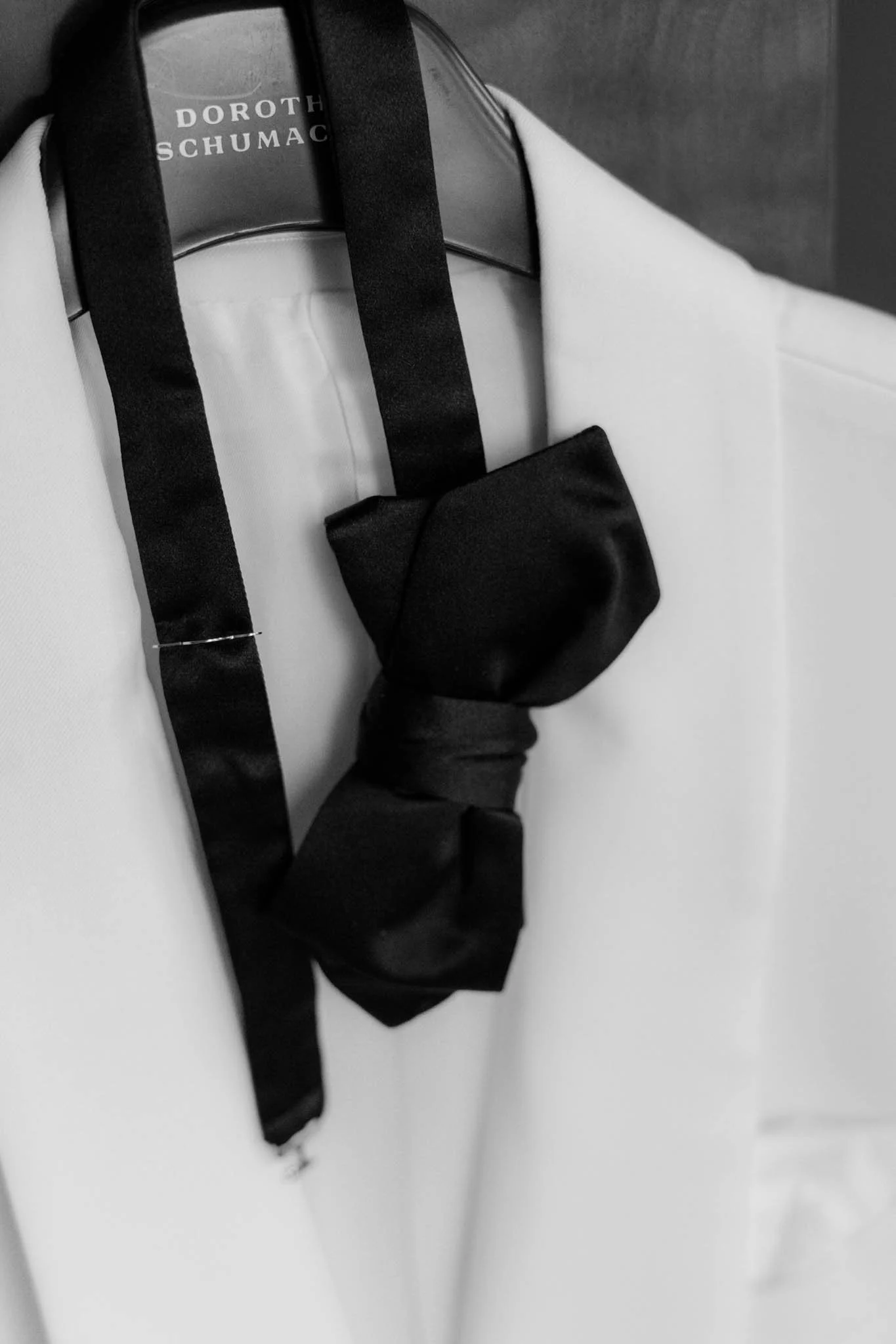 Elegante Schwarz-Weiß-Detailaufnahme beim Getting Ready von Laurin im Hotel Louis C. Jacob in Hamburg. Im Fokus stehen die Schleife und das Jacket seines Hochzeitsoutfits. Die zeitlose Bildgestaltung unterstreicht die stilvollen Details und die beson