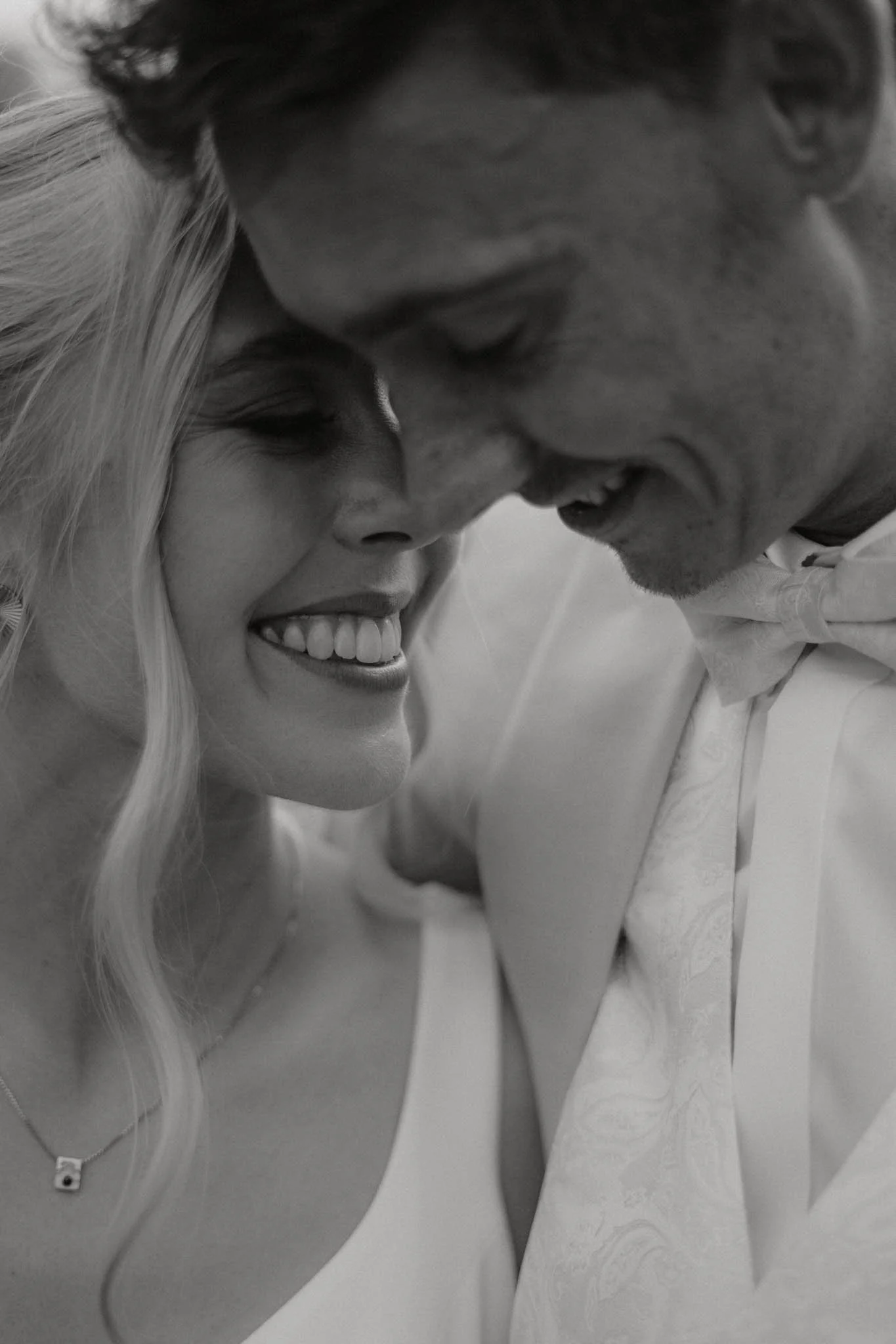 Nahaufnahme eines glücklichen Paares beim Paarshooting, lächelnd und sich berührend, in Schwarz-Weiß aufgenommen.