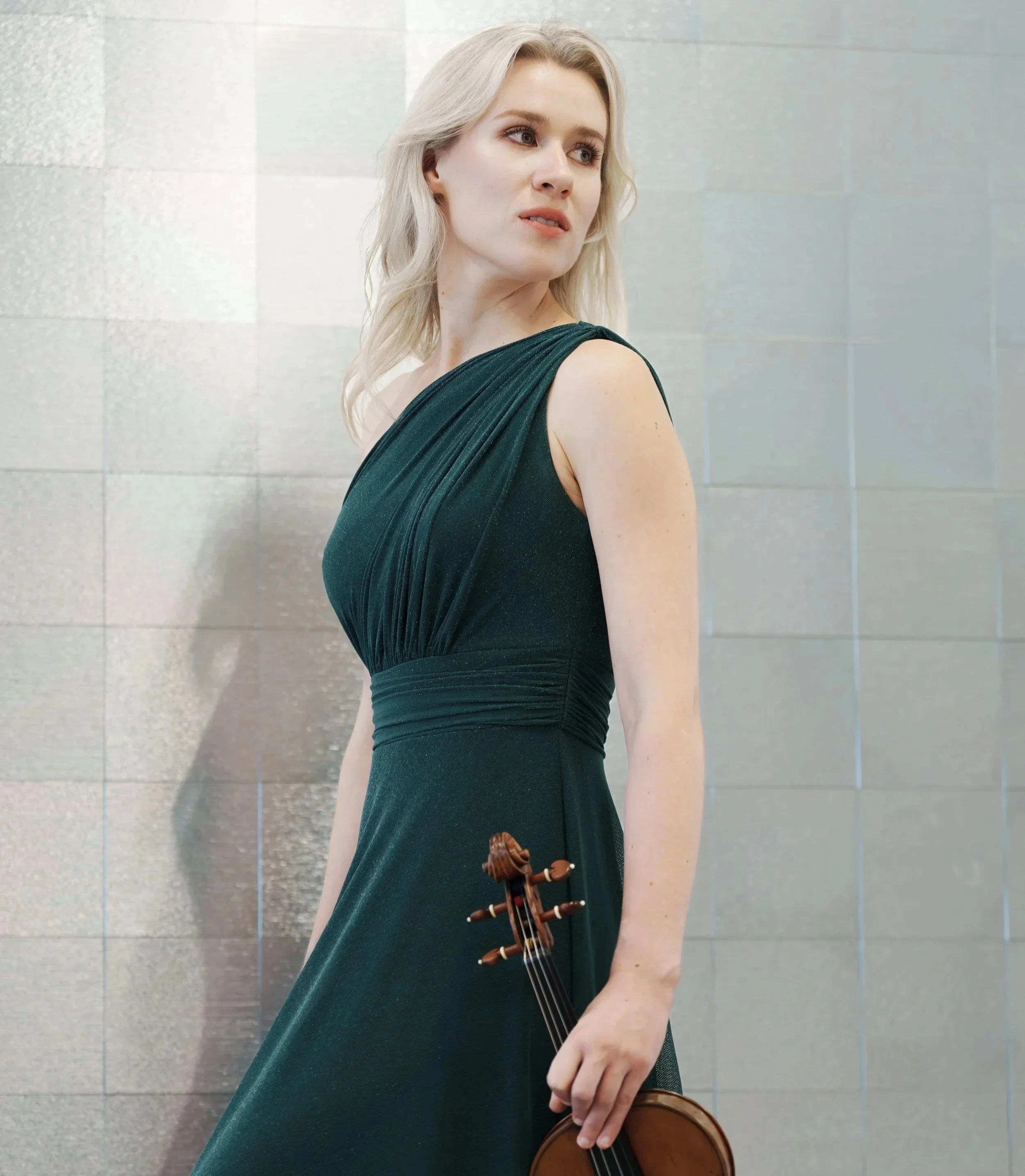 Eldbjørg Hemsing dressed in a dark green gown holding a violin.