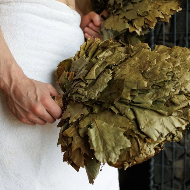 Une personne tient un bouquet de feuilles de vigne séchées.