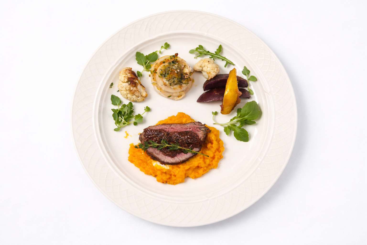 Gourmet plate with sliced cooked meat on orange puree, accompanied by roasted vegetables and garnished with microgreens.