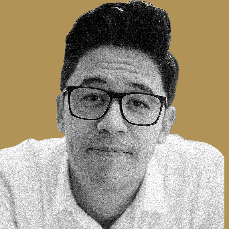 A portrait of a man with dark hair and glasses, wearing a white shirt, against a plain tan background.