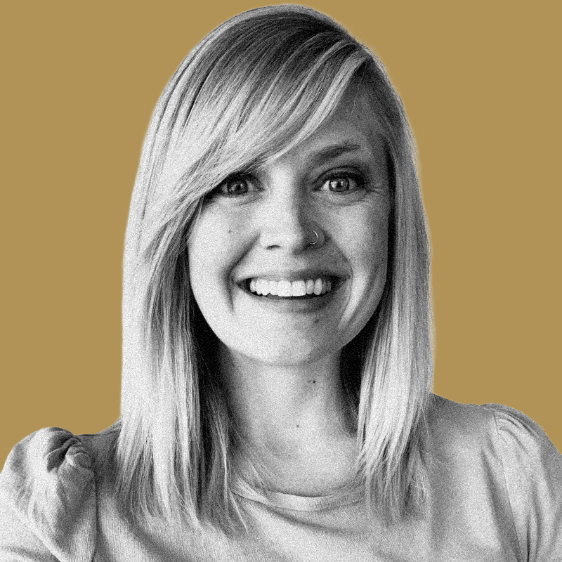 Black and white portrait of a smiling woman with straight hair, wearing a nose ring, against a plain background.
