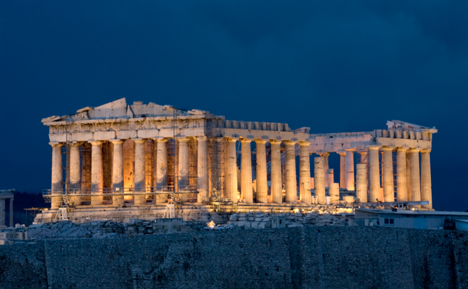 Nighttime view of the illuminated ancient Greek Parthenon temple on the Acropolis in Athens, Greece.