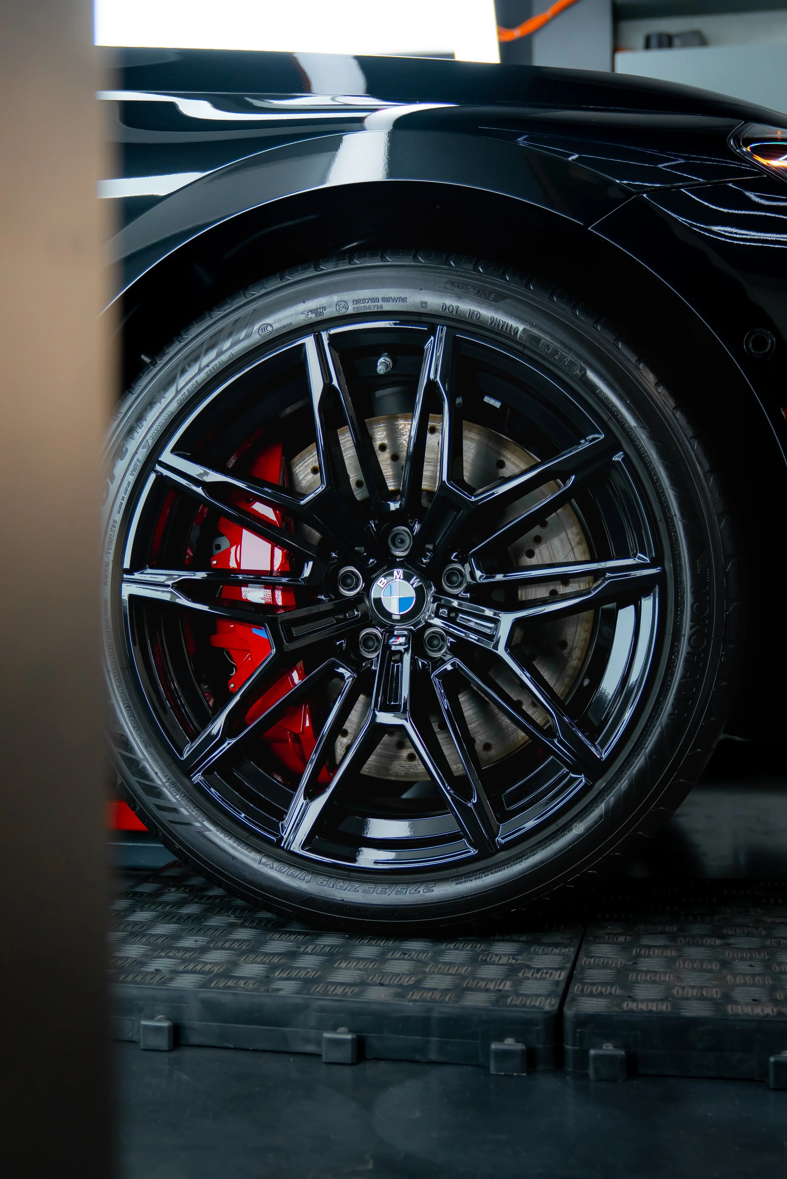 Wheel shot of an M2 gloss black 19" wheel and red caliper after being ceramic coated at ZAutoCare.
