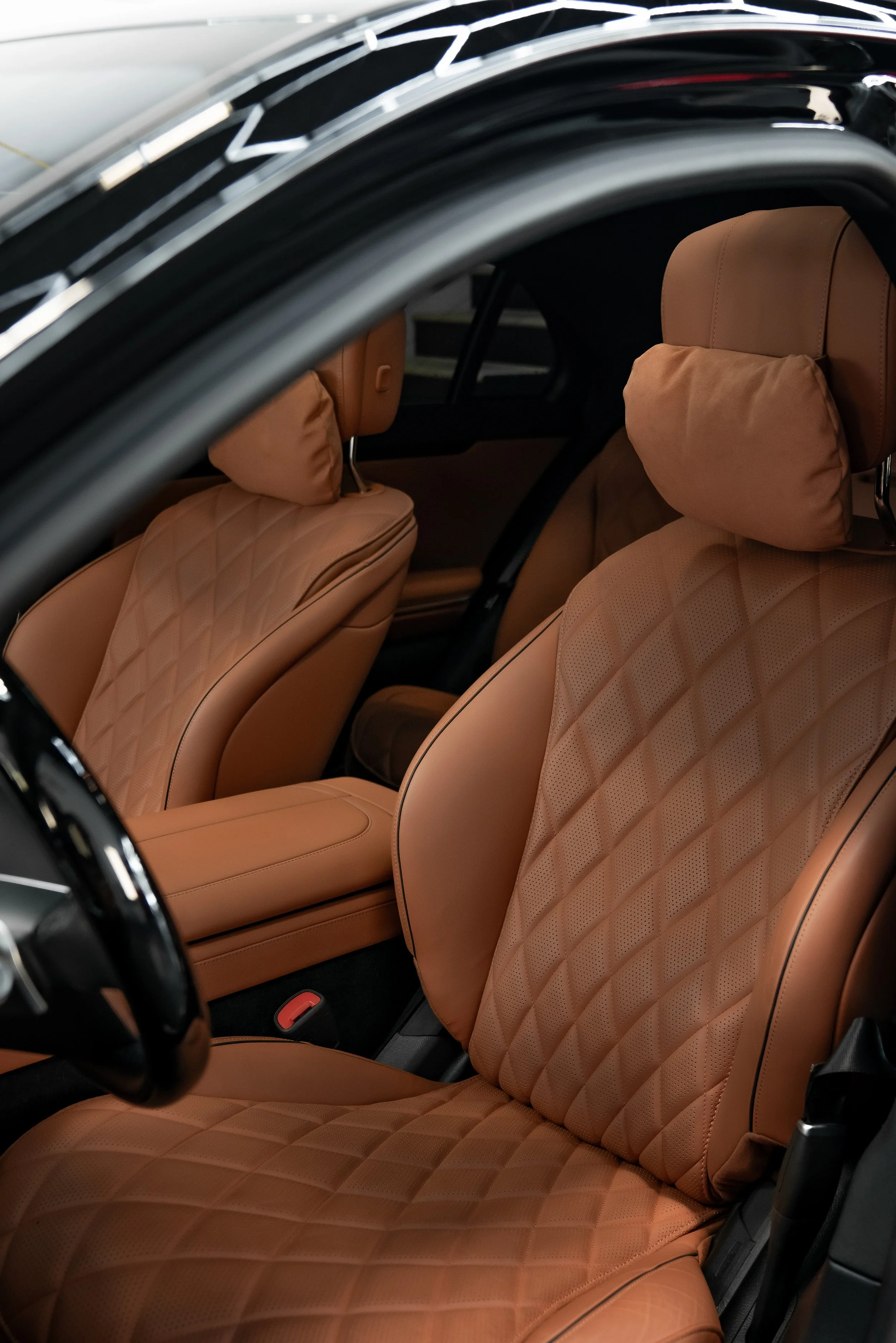 Interior of a Mercedes Brabus with brown leather seats, quilted patterns on the seats and headrests, headrests also have attached pillow cushions.