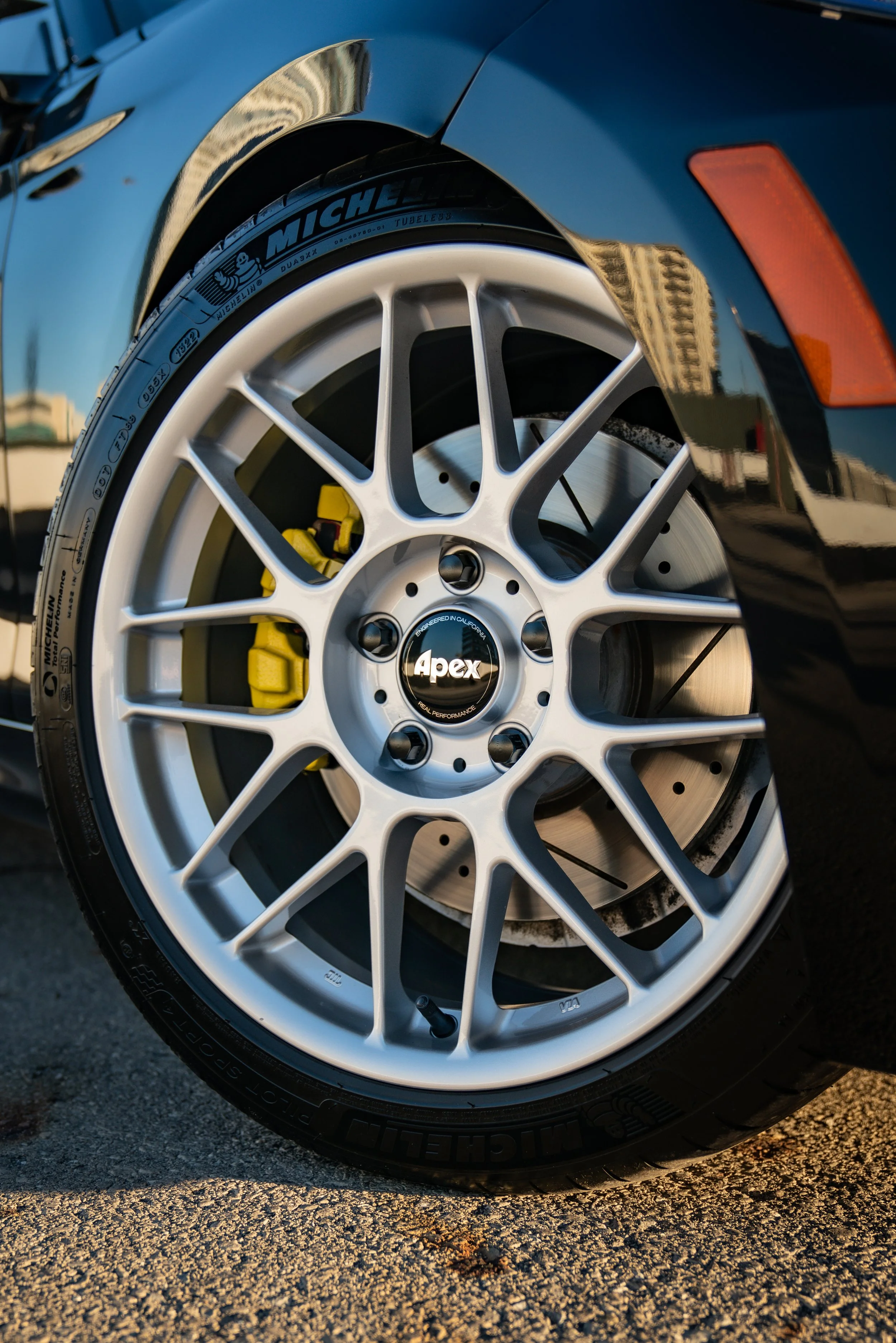 Close-up of a hyper silver APEX ARC-8 with a yellow brake caliper and a Michelin PS4S tire on a BMW 2 series.