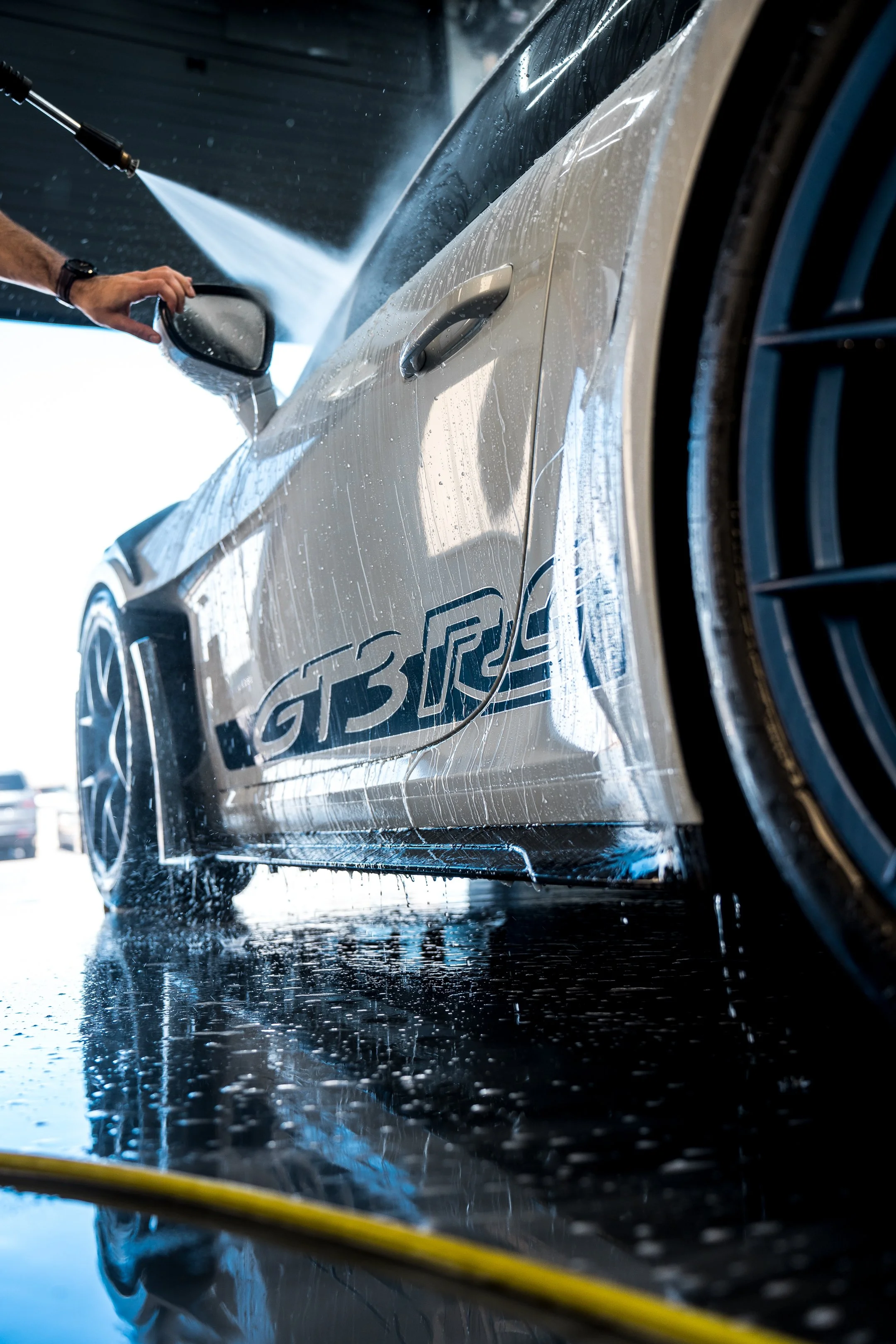 A Porsche GT3 RS being rinsed down by an employee of ZAutoCare after receiving an exterior wash.