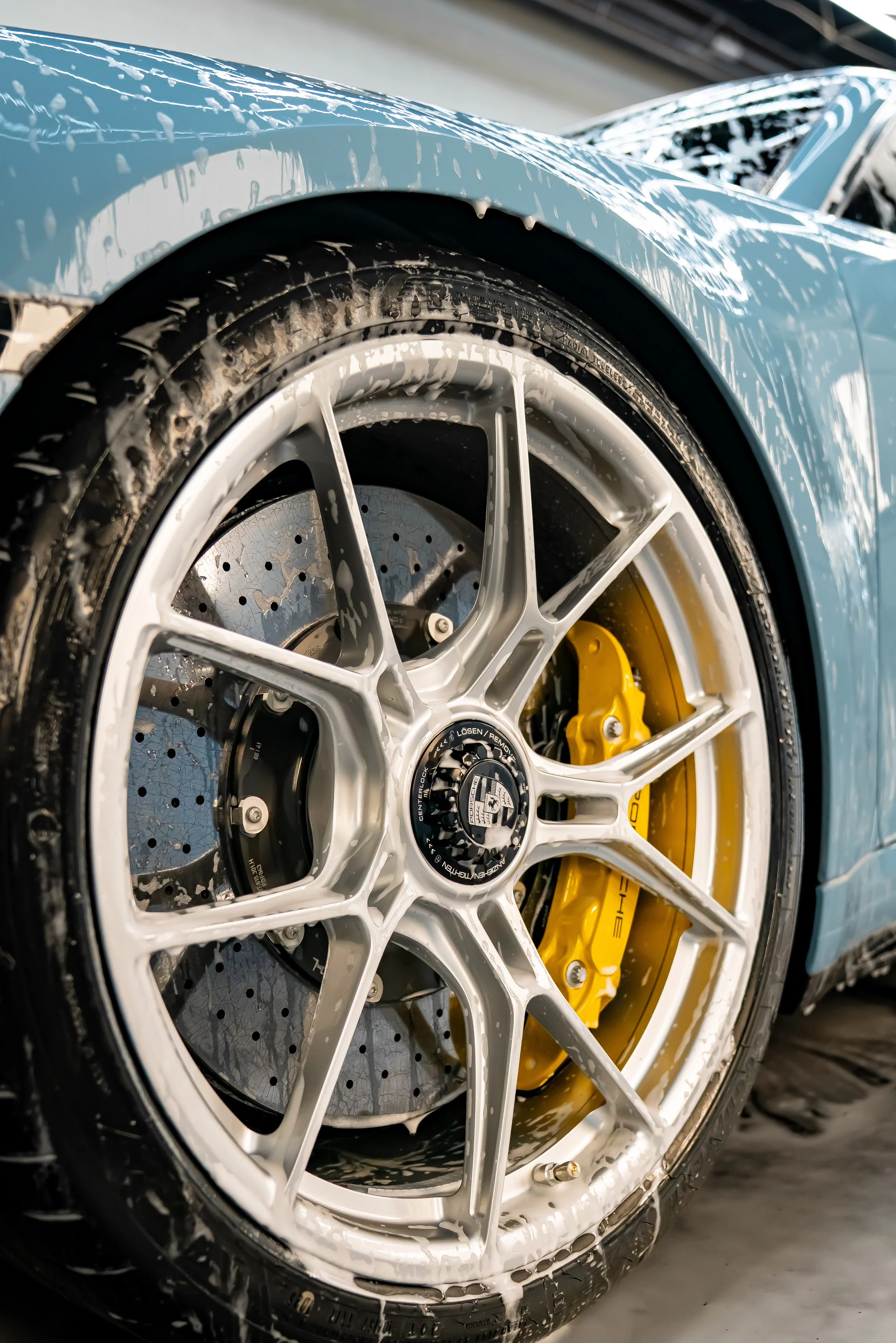 professional car detailing wheel cleaning foam brake caliper alloy rim luxury auto detailing service.