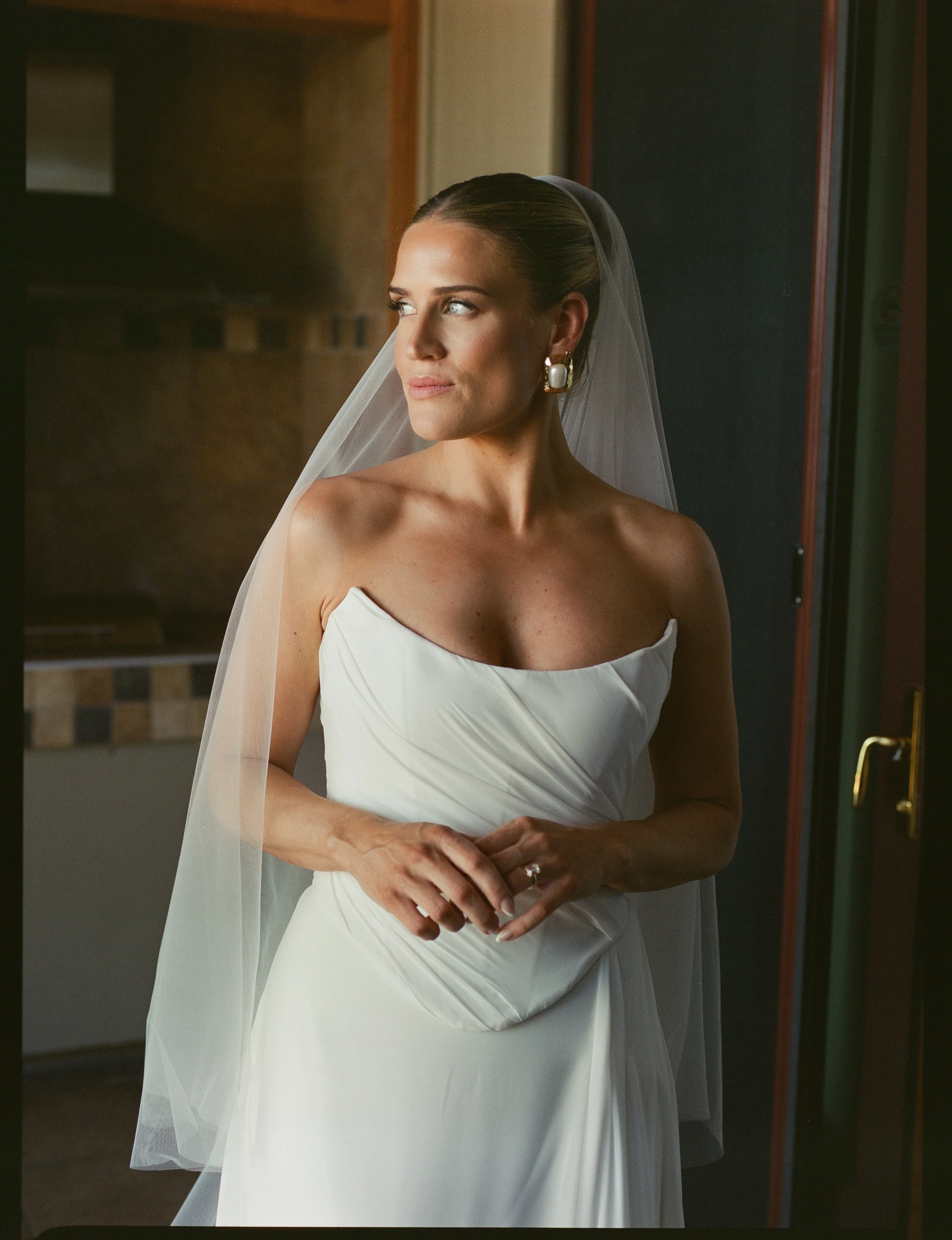 Bridal makeup and hair - bride looking out the window in wedding dress