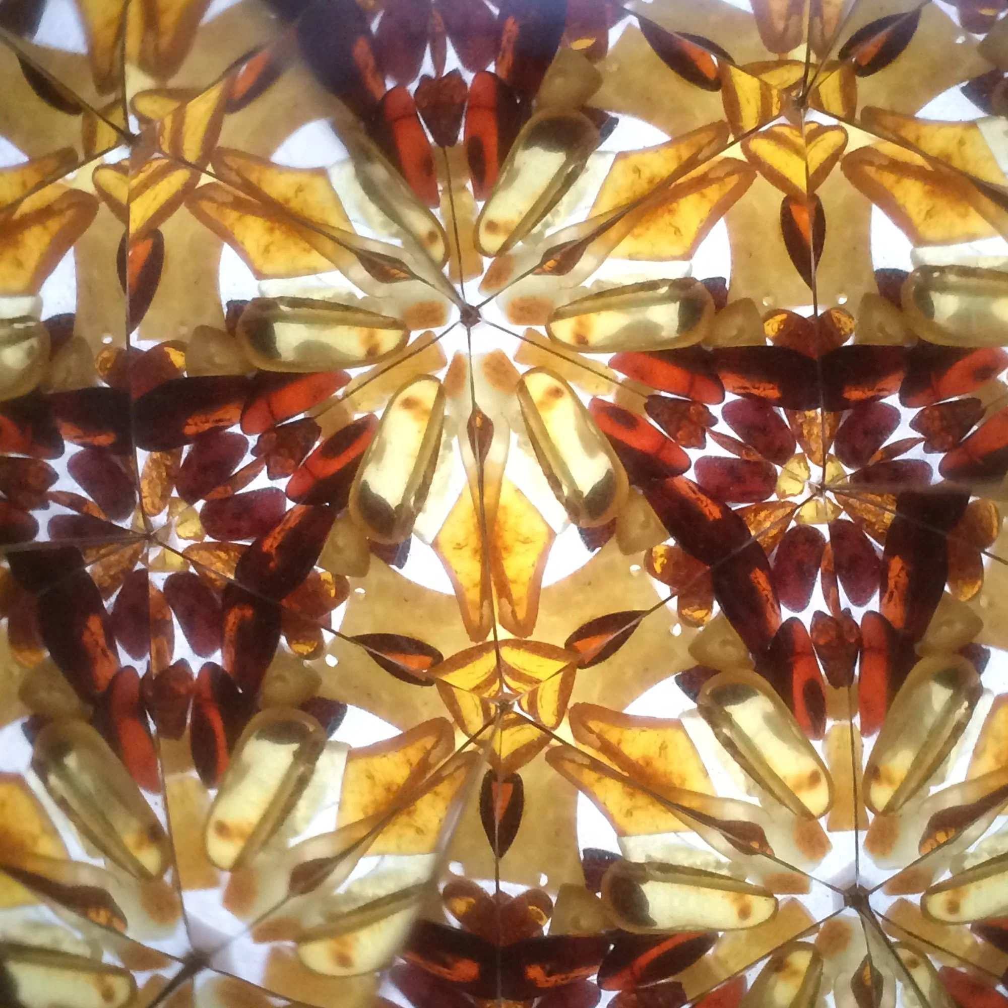  Symmetrical amber mandala featuring a prominent hexagonal star pattern made from a mix of bright yellow and deep reddish-brown resin. 
