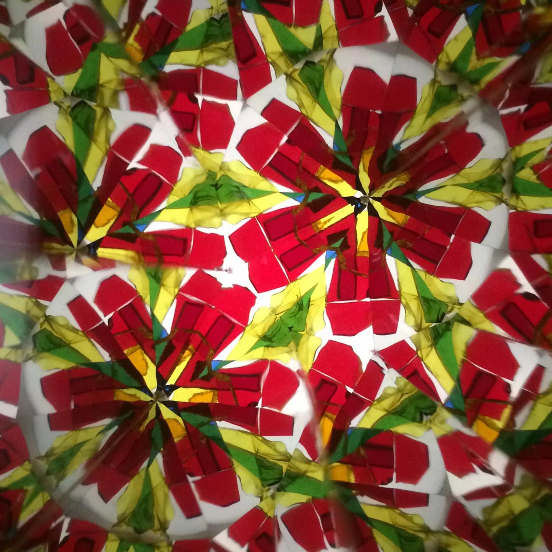  Symmetrical pattern of brilliant red glass flower petals with yellow accents, creating a large blooming star motif on a white background. 