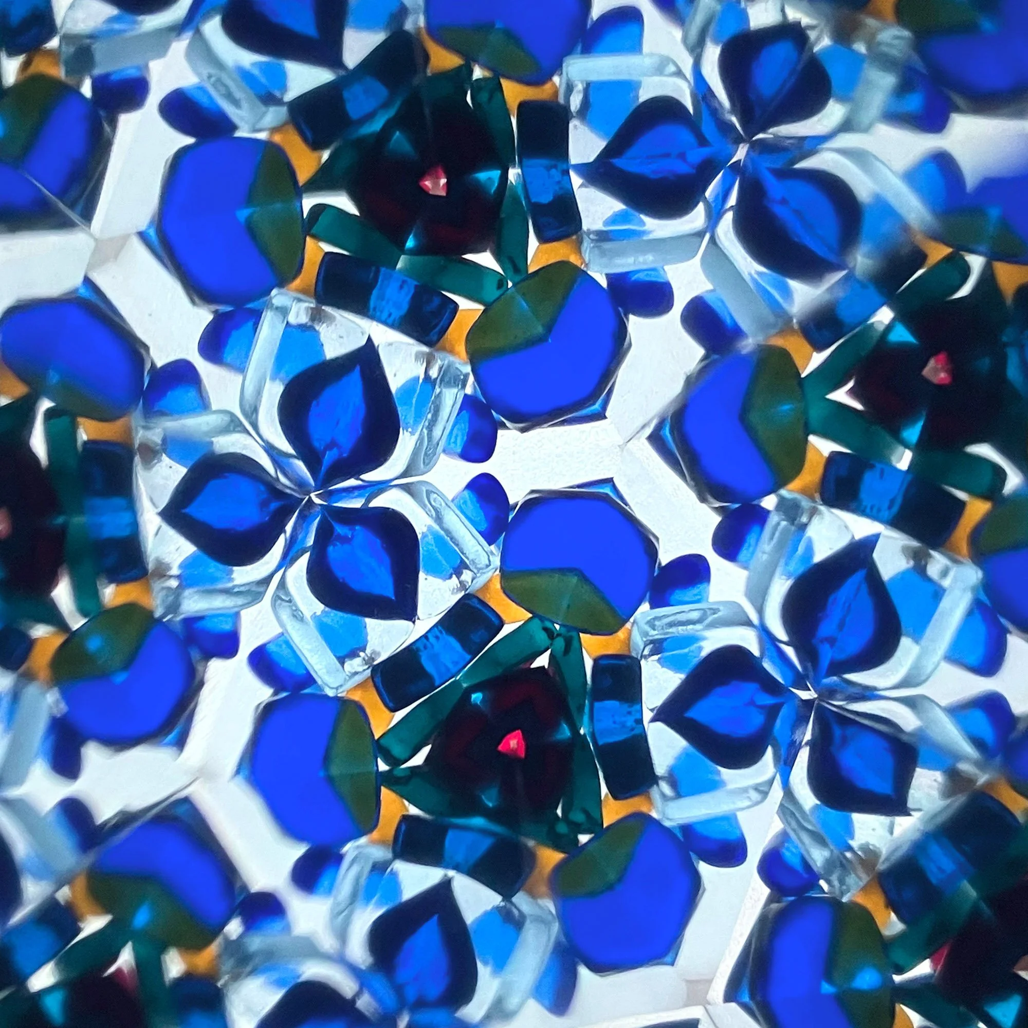  Dense blue glass kaleidoscope composition with layered radial symmetry, resembling ornamental tilework and repeating geometric motifs. 