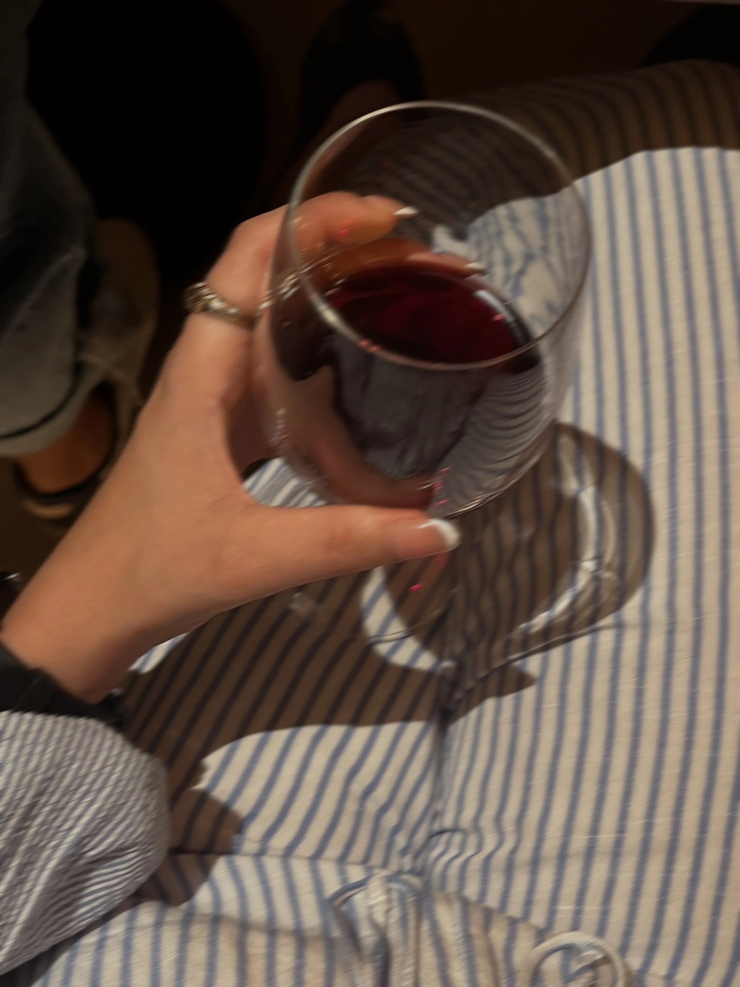 A blurry photo of a woman holding a wine glass