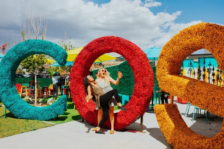 Two people pose before large letters