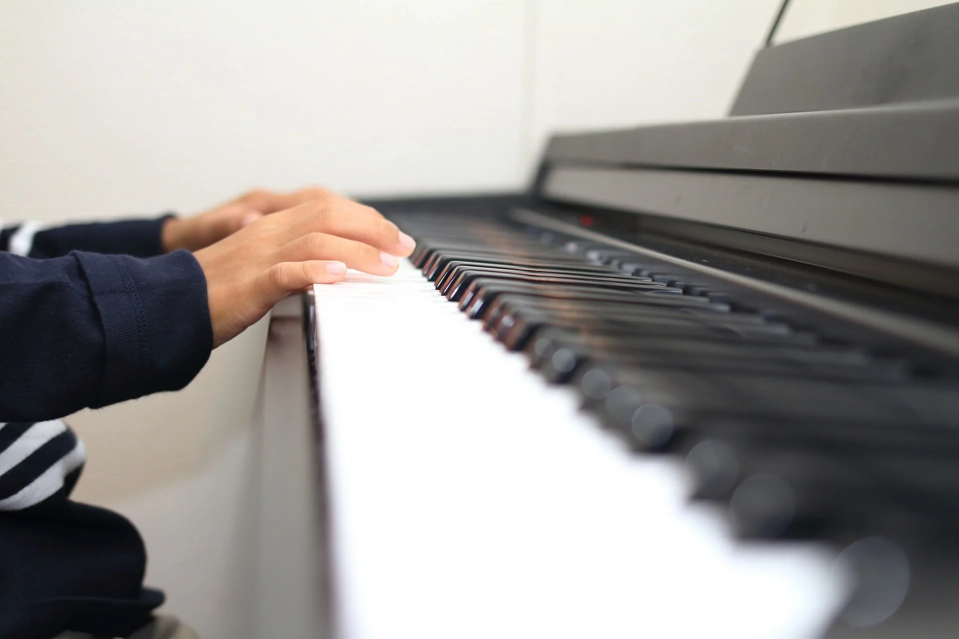 Close-up of a child’s hands playing piano keys during a music lesson.