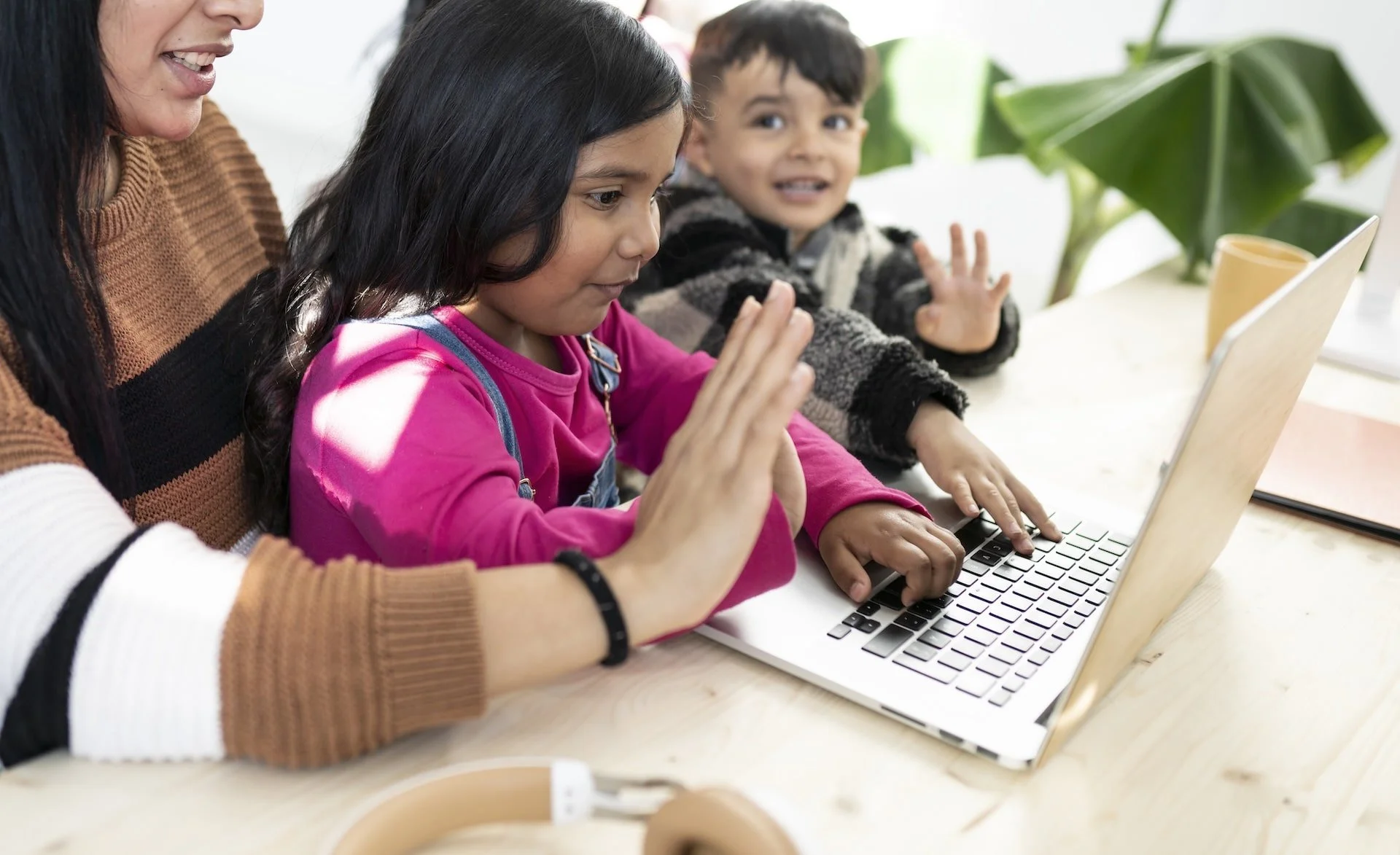 Mother helping her children participate in an online learning activity using a laptop.