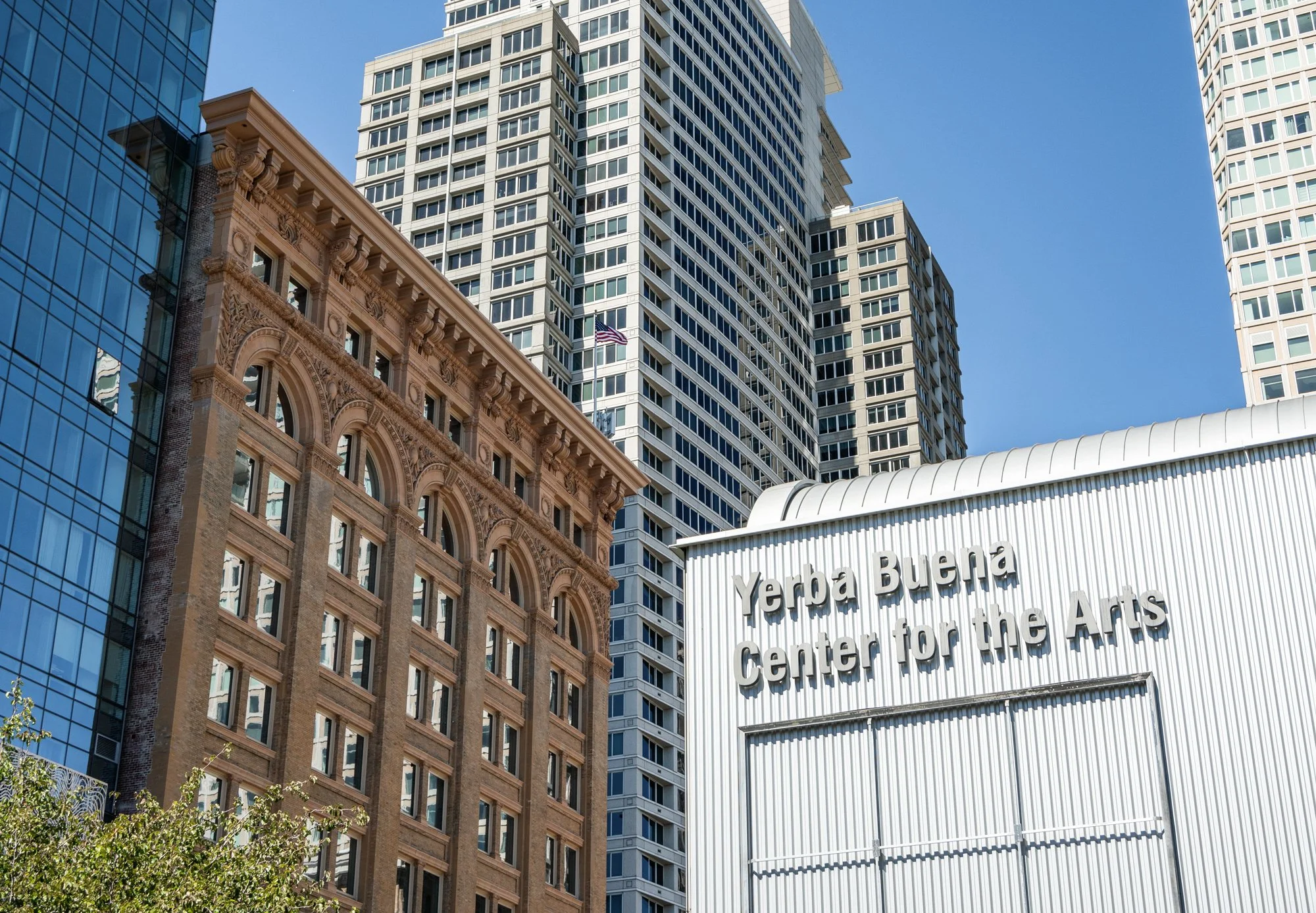 Skyline of tall buildings, including the Yerba Buena Center for the Arts, with a clear blue sky.