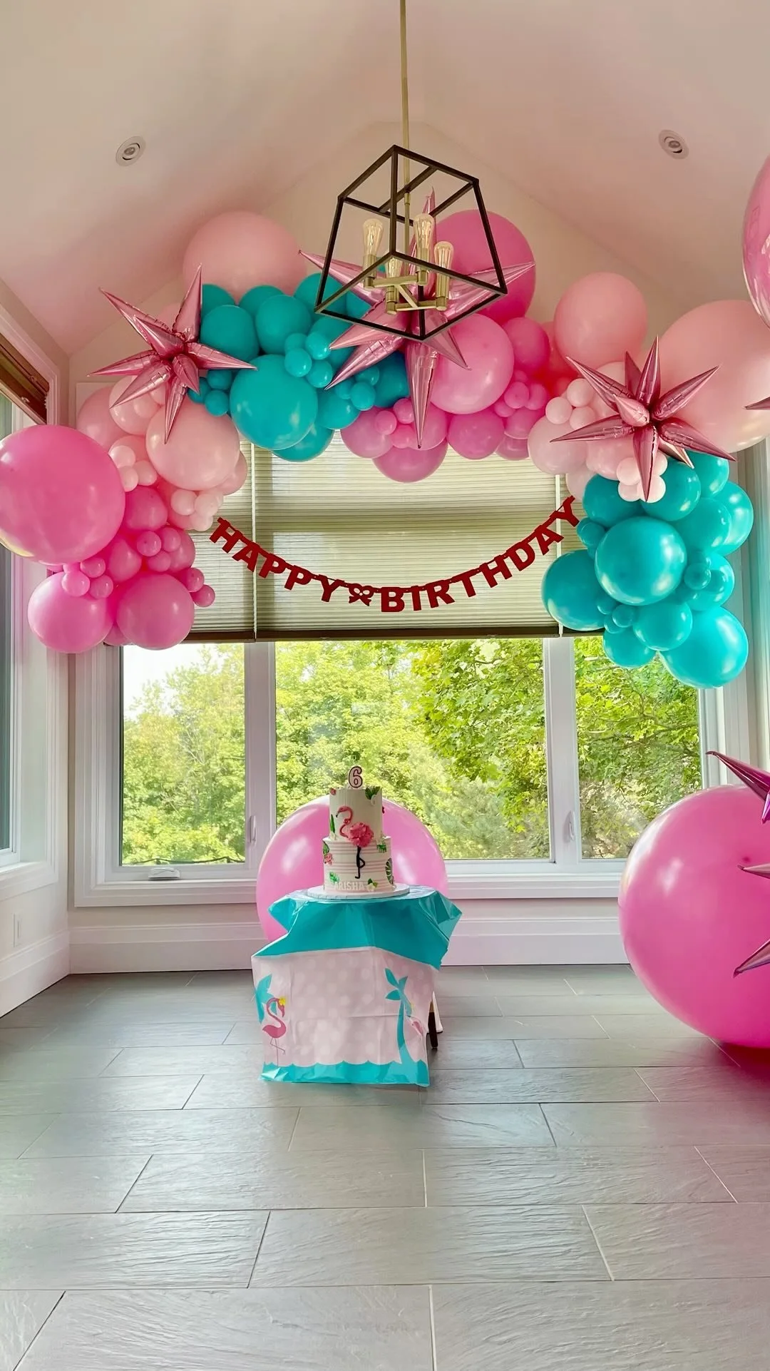 Decorated birthday celebration area with balloon arch in pink and teal, a