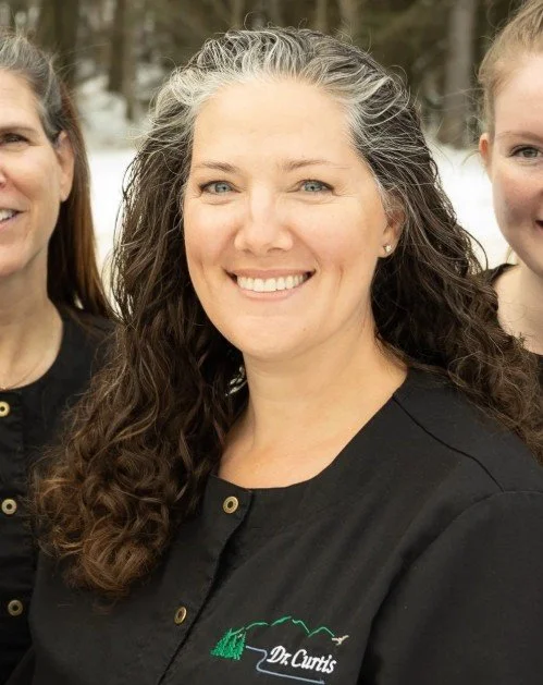 Dr. Curtis with curly hair wearing a black shirt with a logo