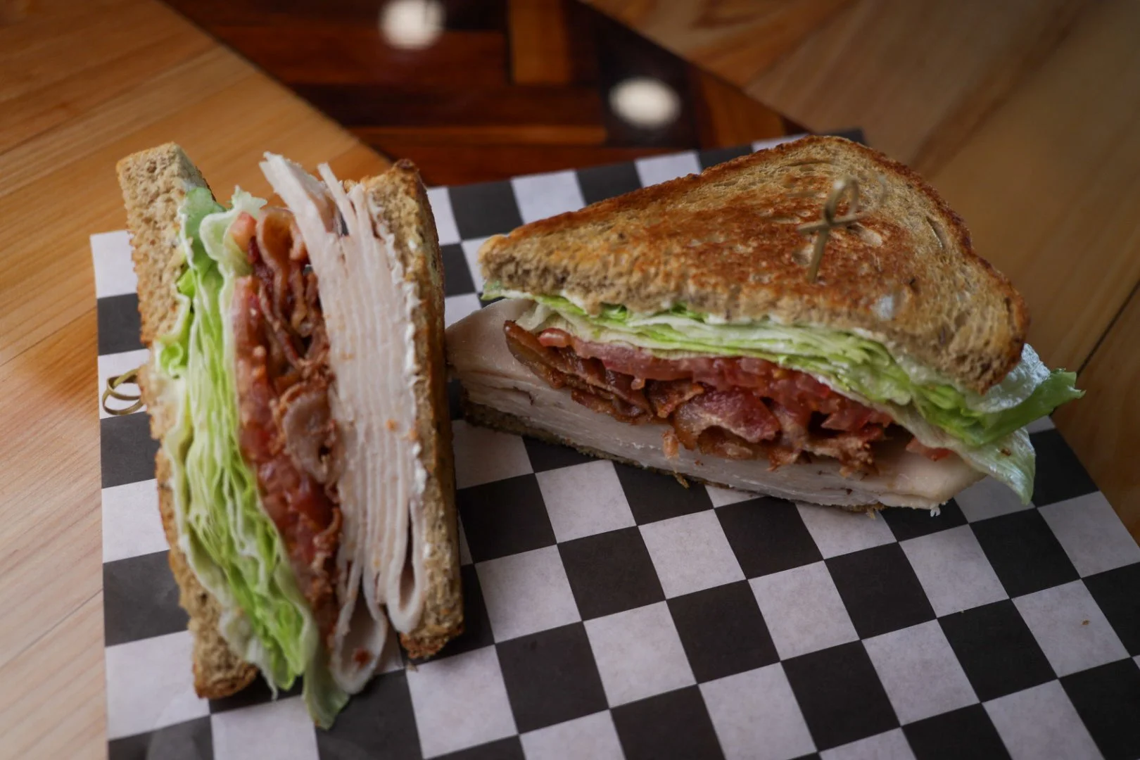 Basket of spicy buffalo chicken wings with celery and carrot sticks, accompanied by a small cup of ranch dressing, with a bottle of Coors beer in the background.