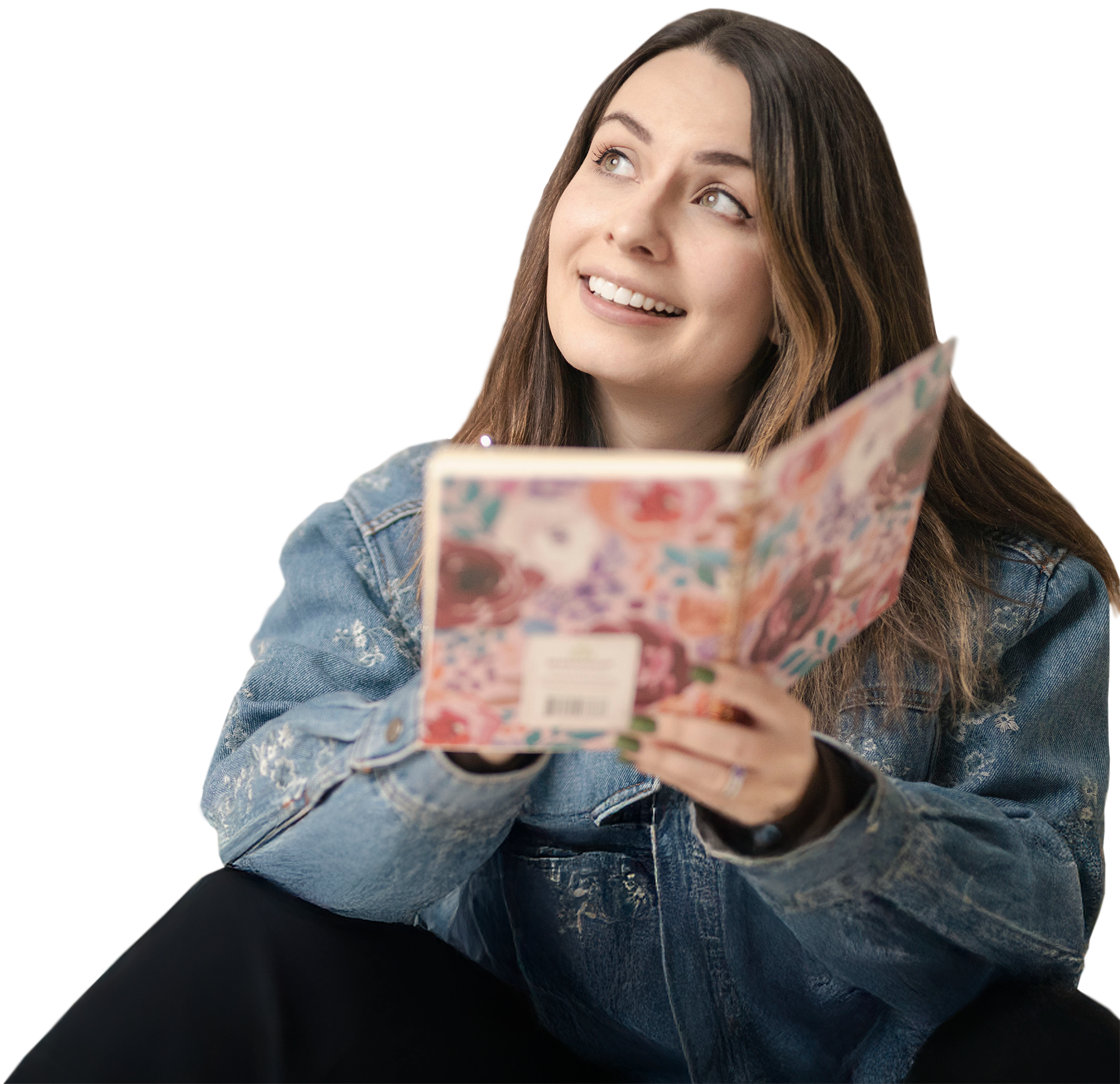 A picture of Olivia smiling and writing in her notebook as she sits, thinking.