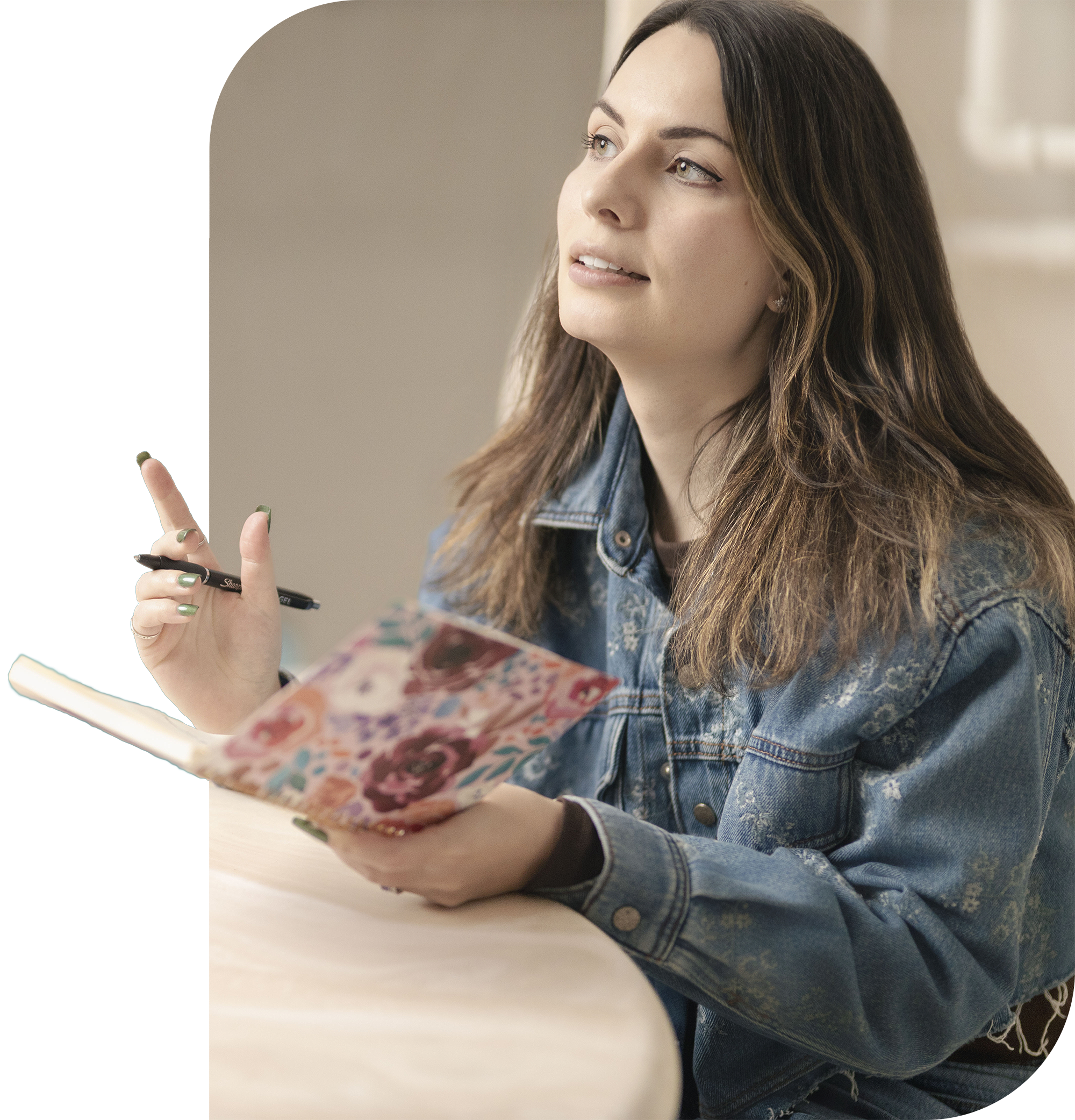 A picture of Olivia sitting with her notebook open and pointing with a pen in her hand.