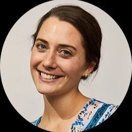 Margaret with her brown hair up in a bun, blue yes, and her head slightly tilted smiles at the camera.