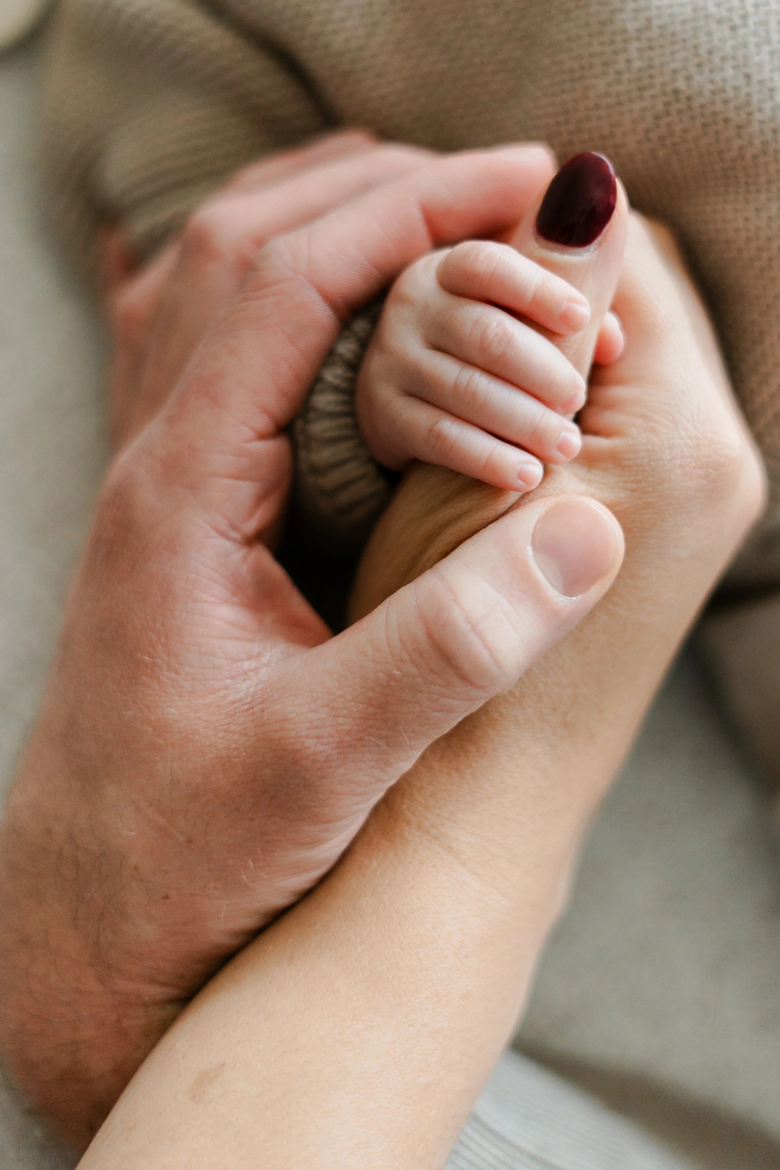 Een volwassene houdt een babyhand vast.