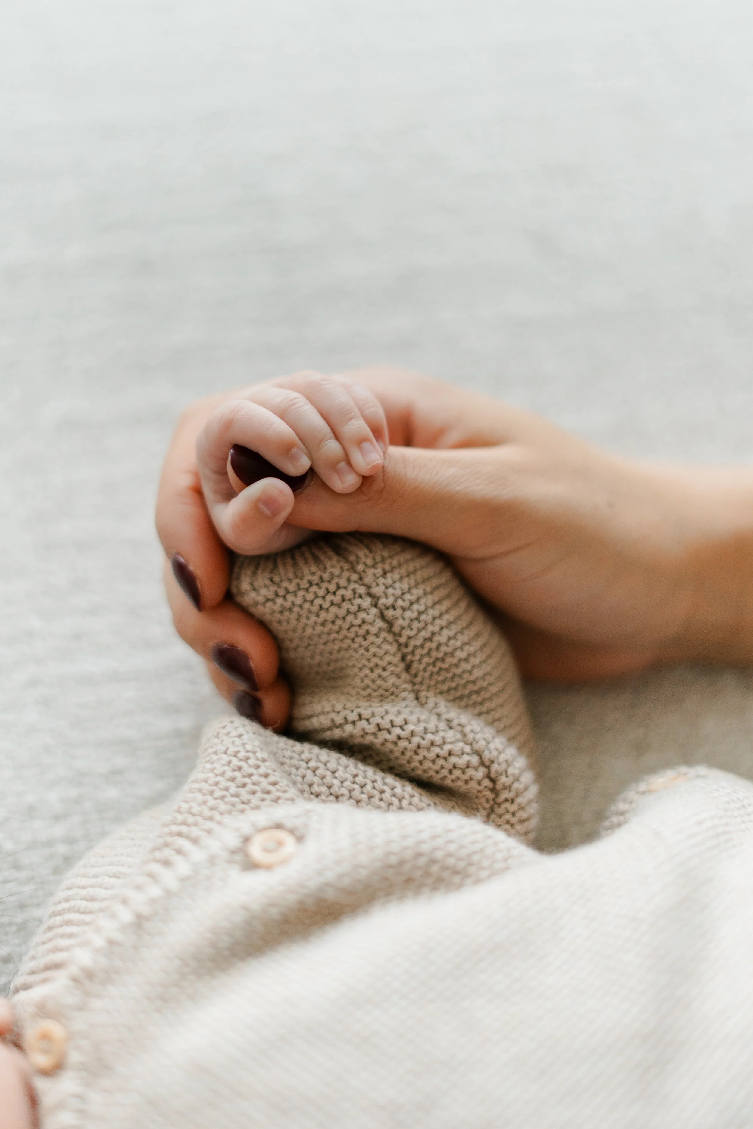 Een menselijke hand die een babyhand vasthoudt.