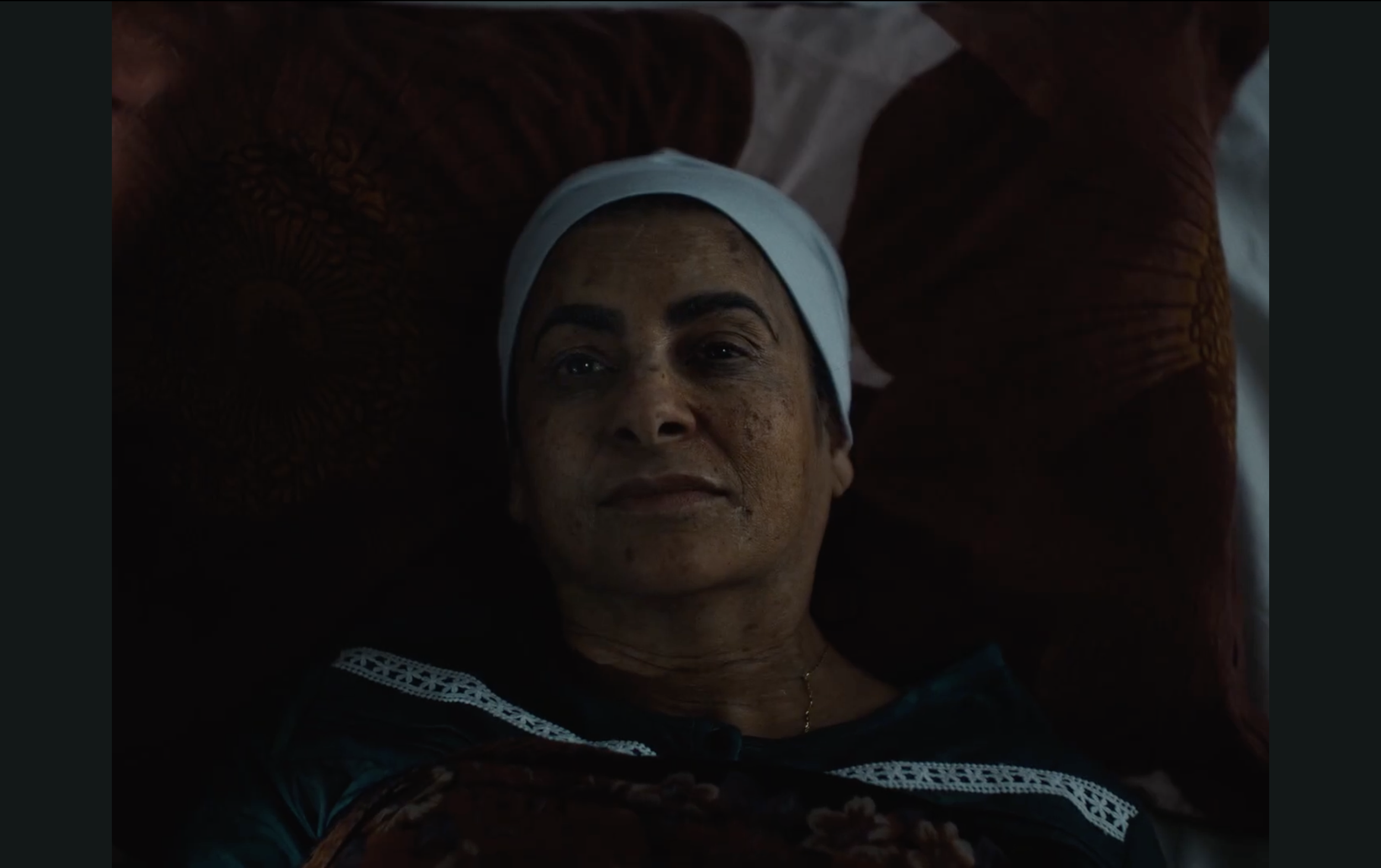A woman lying in bed with a white headband, looking relaxed with a serene expression.