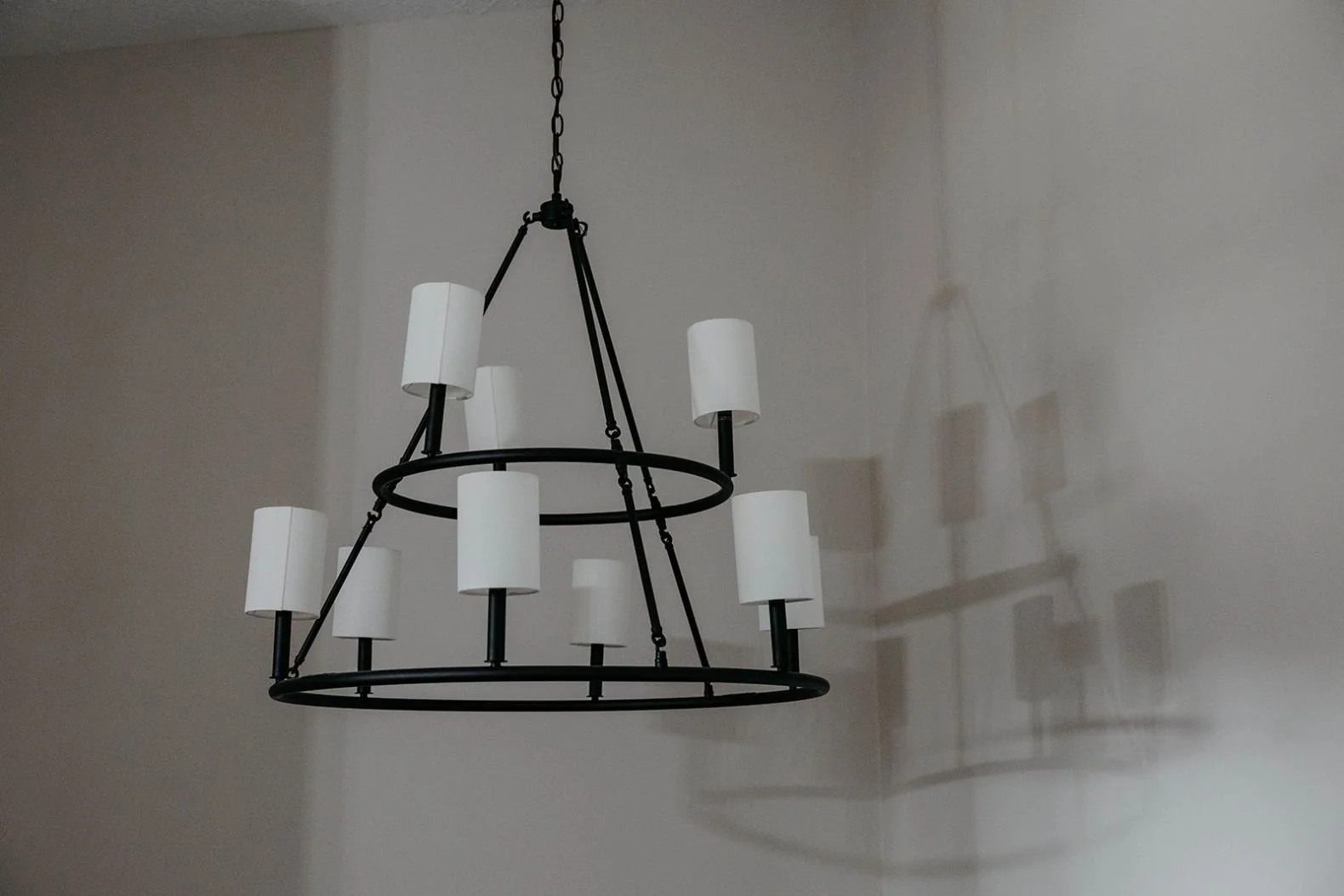Close-up of a transitional black chandelier with a curved frame and ten white candle-style lights.