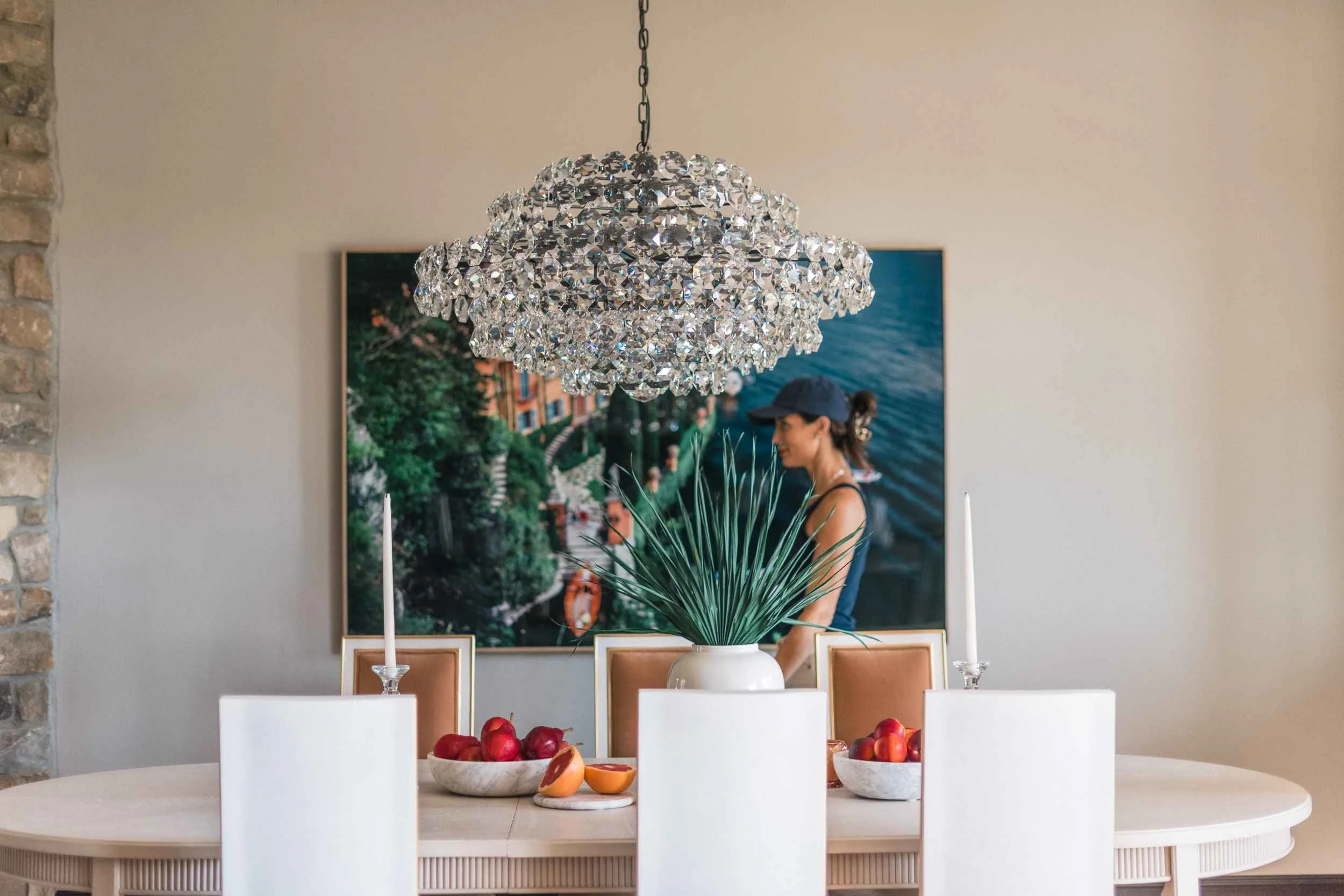 Wide view of the crystal chandelier and the dining table, centered on a large wall art print featuring Christy Steen in the background.