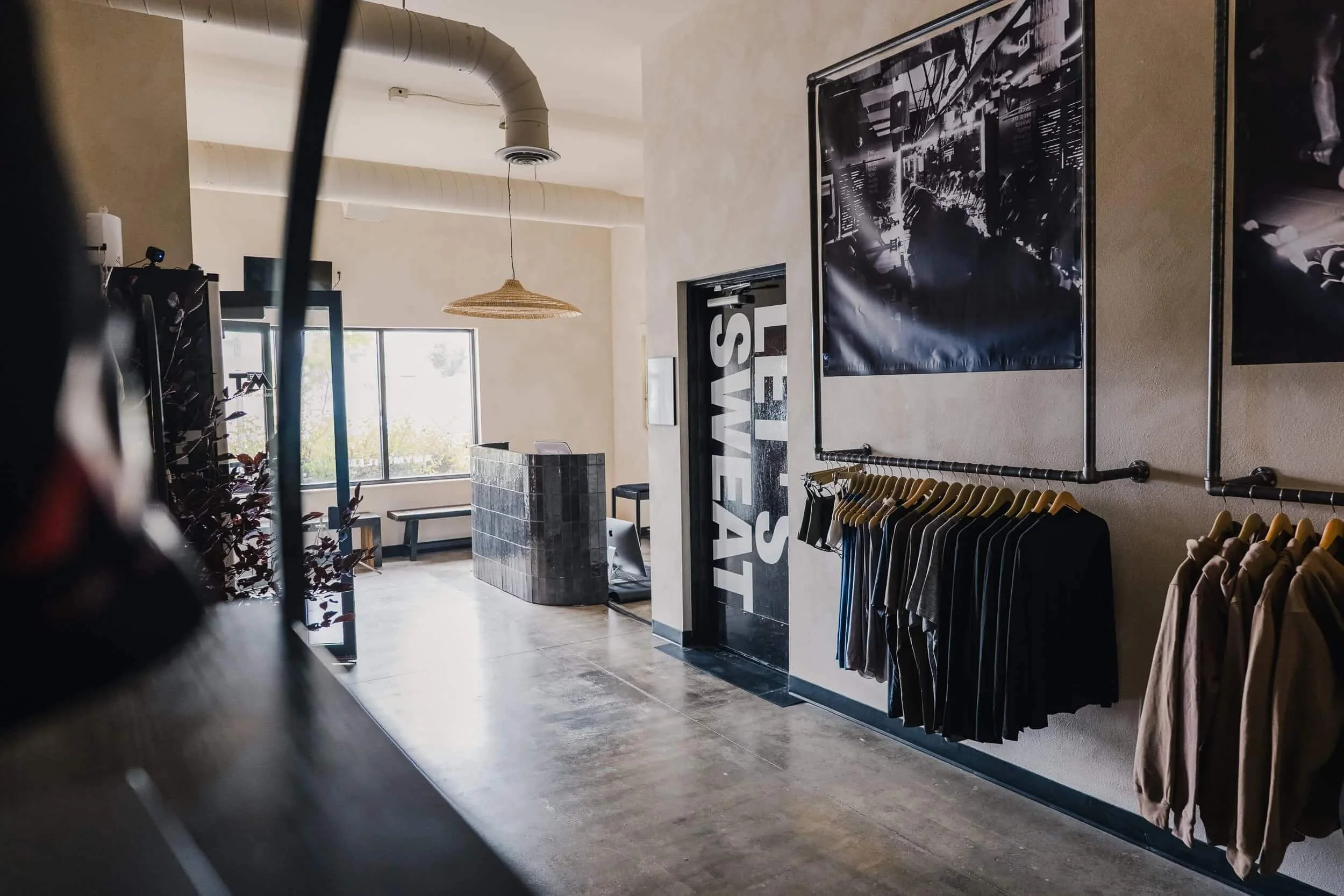 View of the retail area showing the clothing racks, large framed artwork, and exposed structural ceiling.