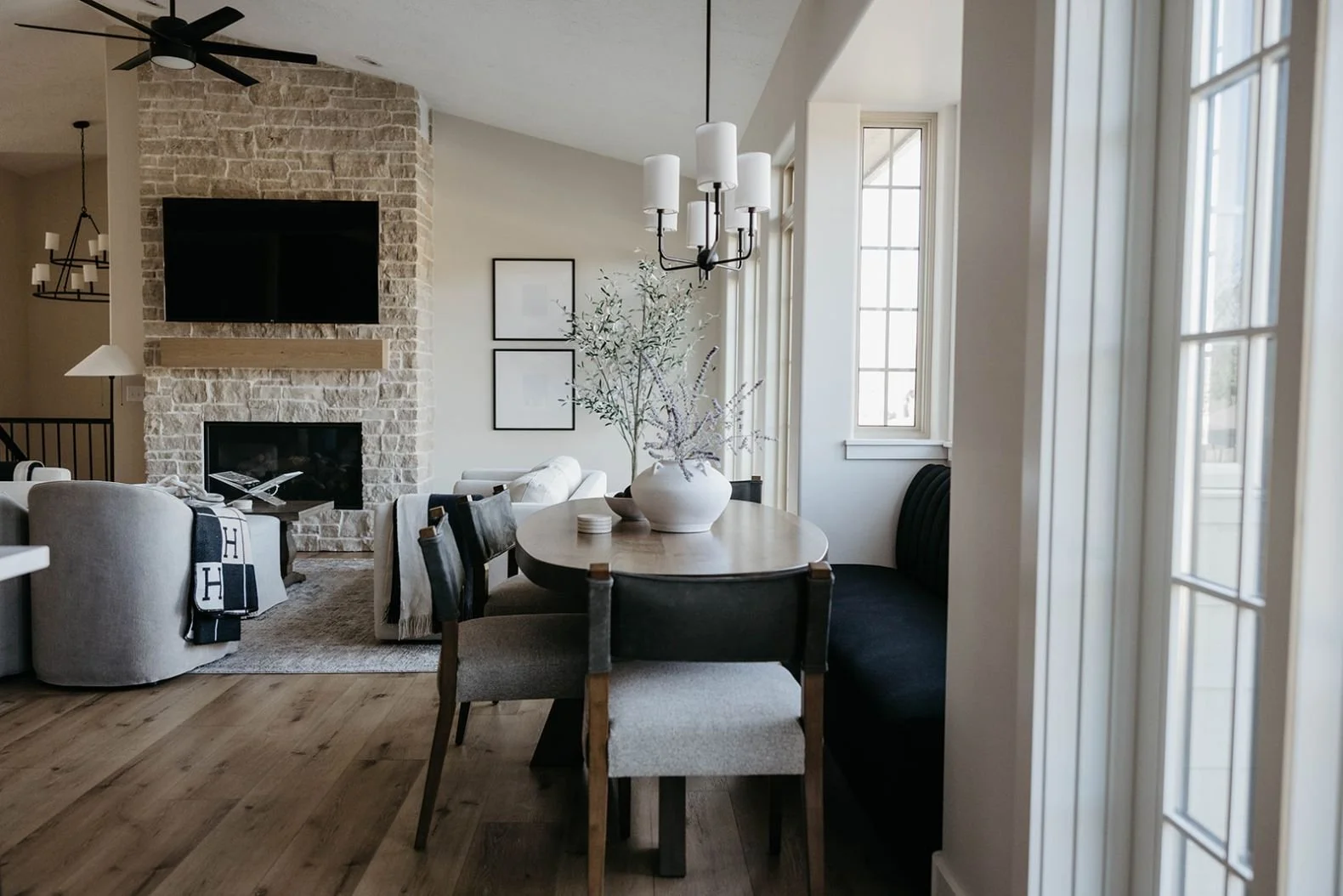 Perspective shot connecting the dining nook to the living room, with the stone fireplace and sitting area visible in the background.