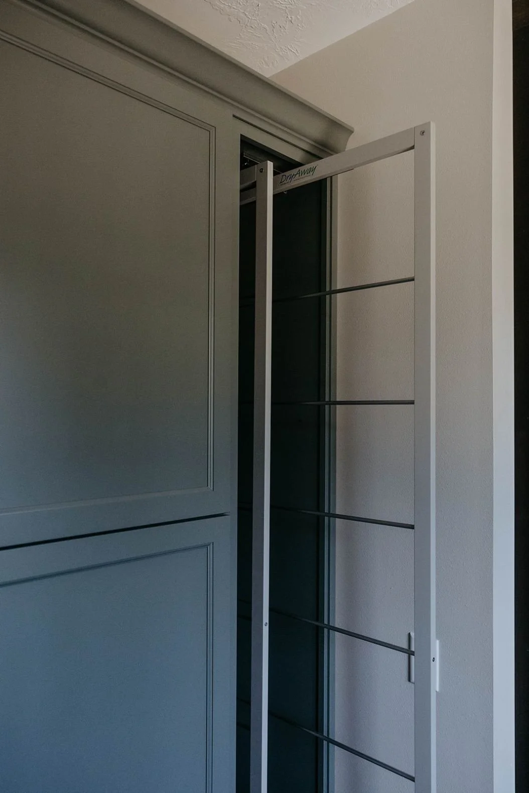 Open utility cabinet in the laundry room with narrow adjustable shelving, showcasing its built-in organization.