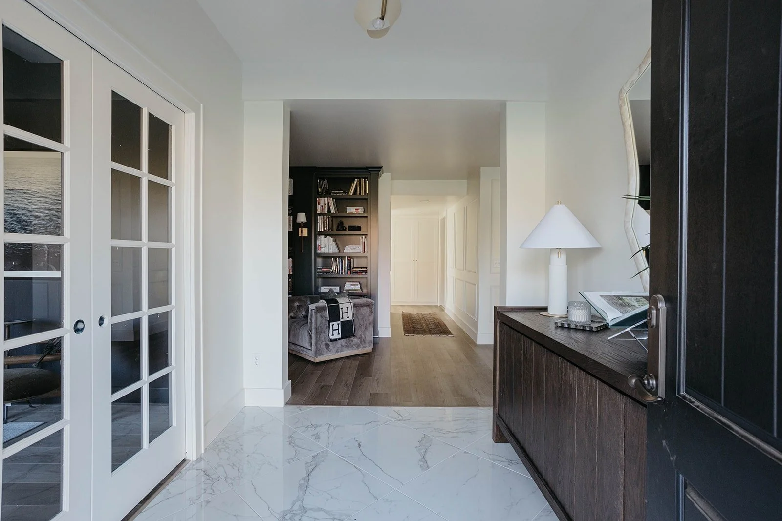 Entryway with white French doors leading to a closet or adjacent room, and a dark wood console cabinet visible on the right.