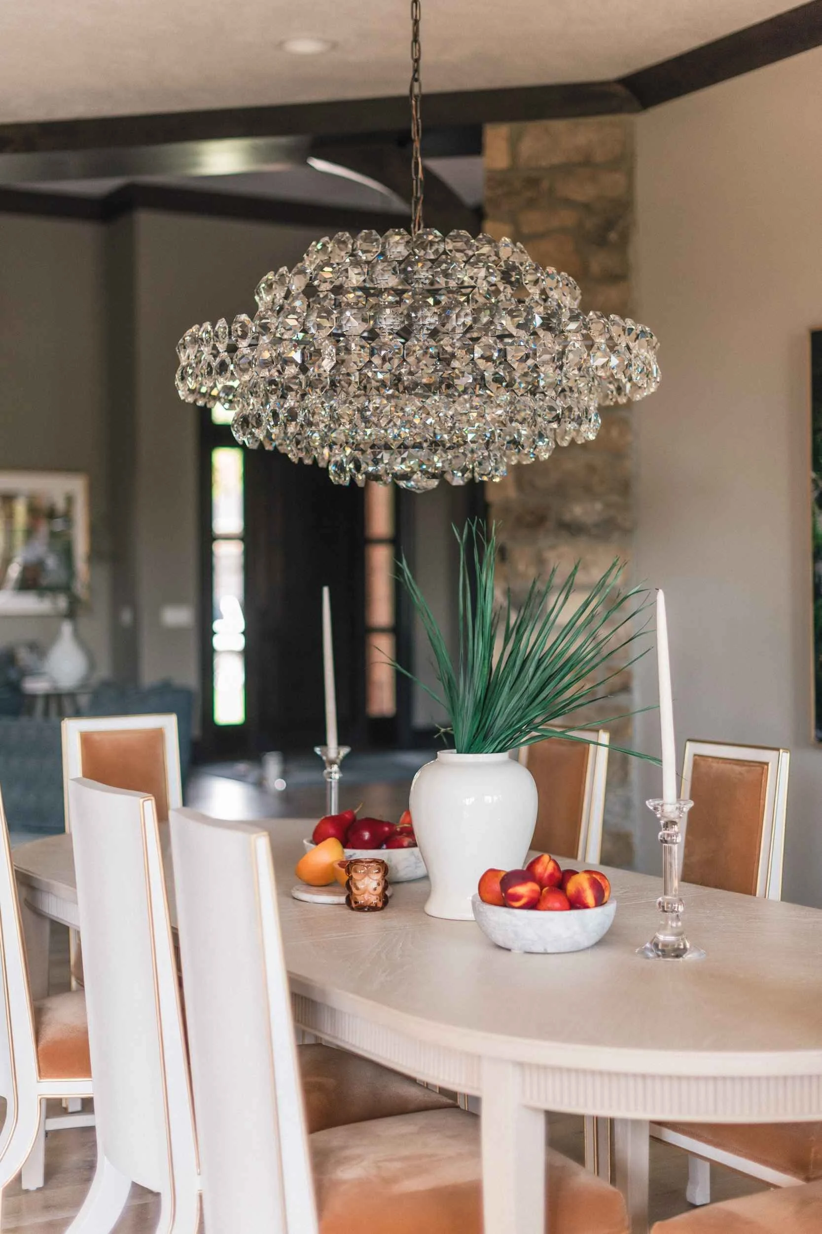 View emphasizing the crystal chandelier and the stone column accent, showing the high-backed dining chairs.
