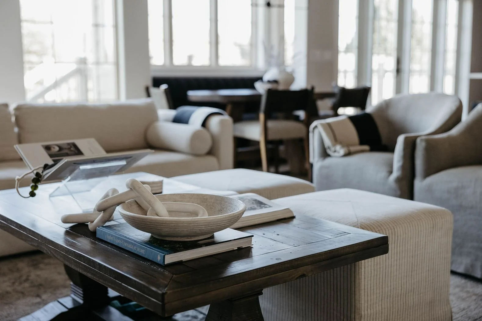 Detail of the dark wood coffee table and the neutral upholstered seating, showing books and accessories on the table's surface