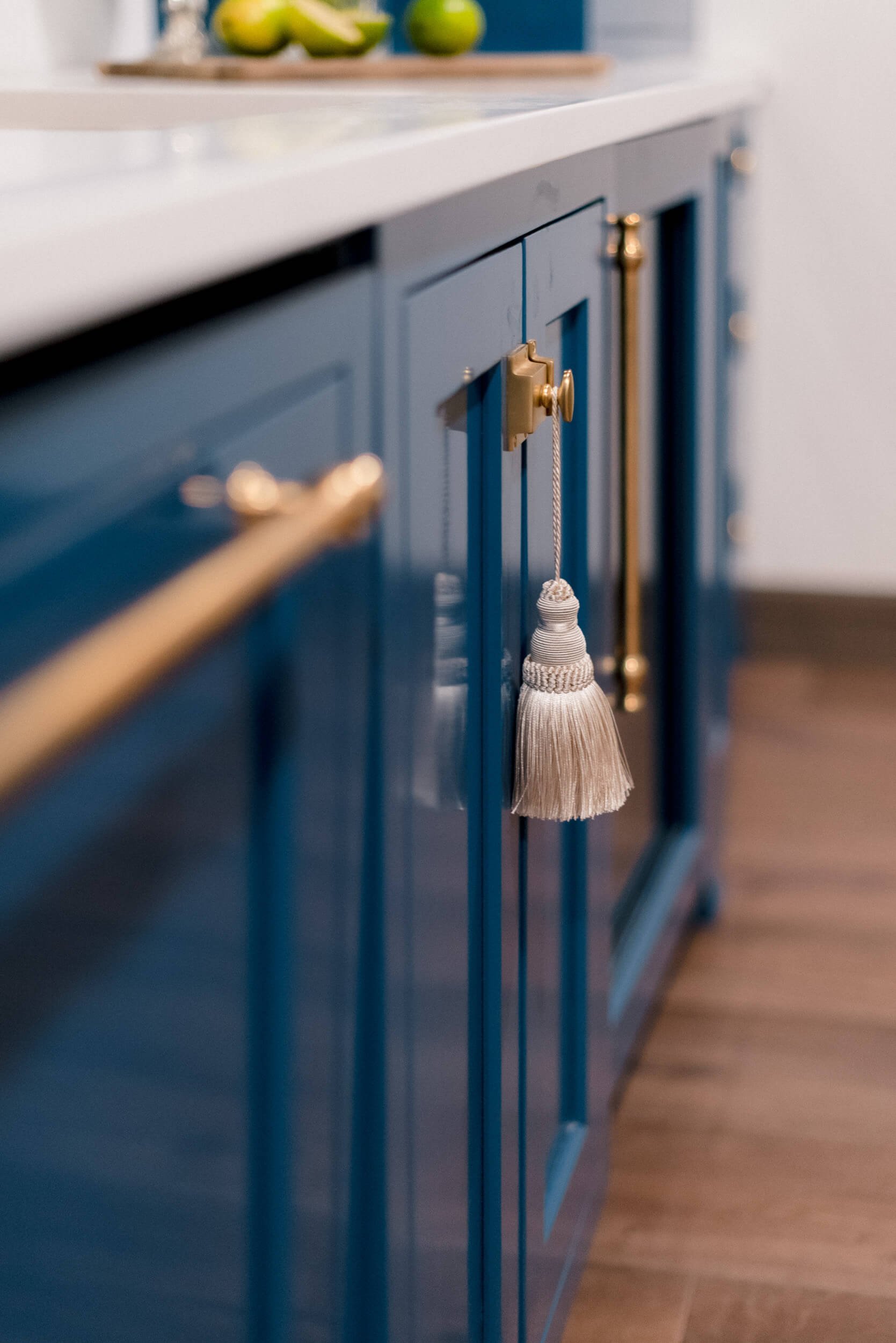 Detailed view of the blue cabinet doors and a long, horizontal brass pull handle accented with a decorative gray tassel.